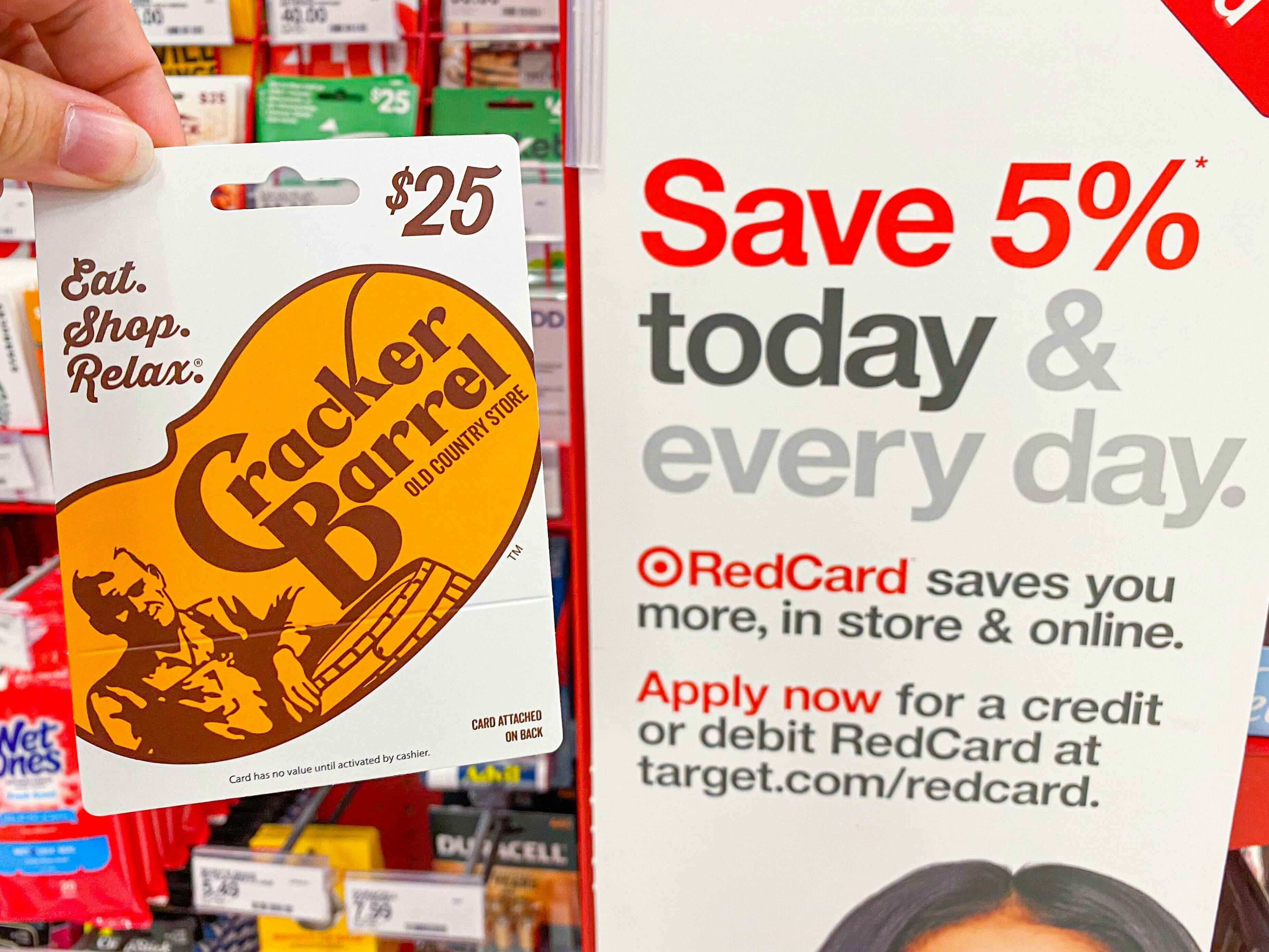 A person's hand holding a Cracker Barrel gift card next to an advertisement for the RedCard at Target.