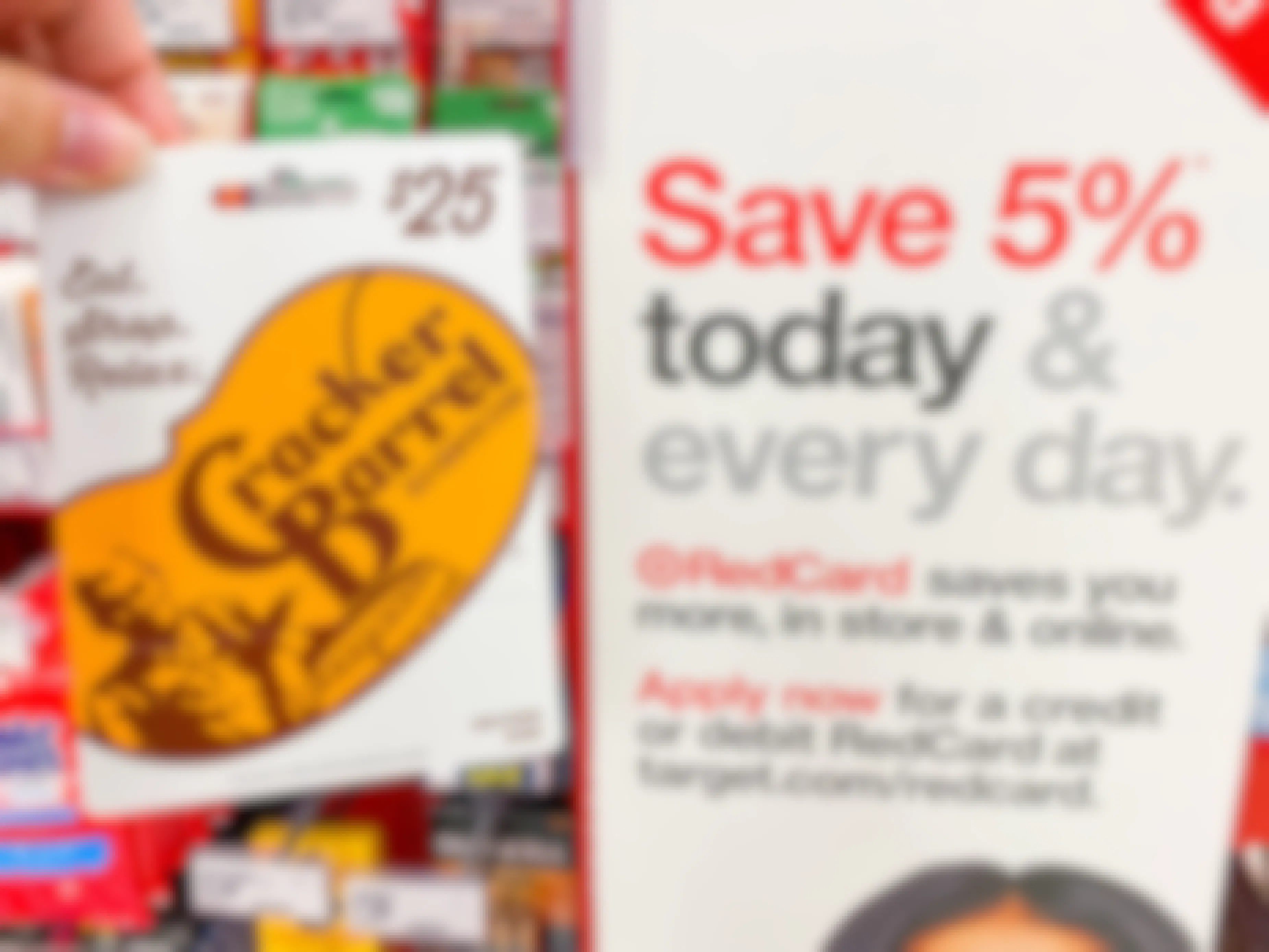 A person's hand holding a Cracker Barrel gift card next to an advertisement for the RedCard at Target.