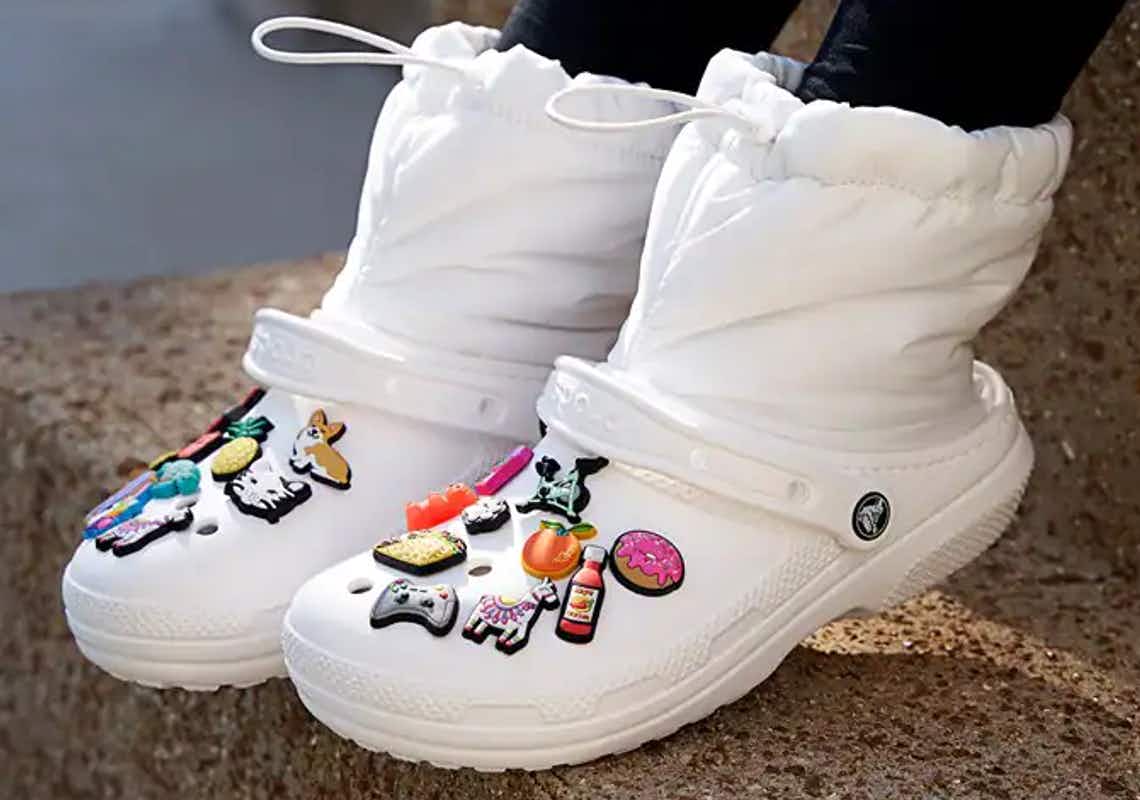 white pair of crocs neo puff boots with charms on them