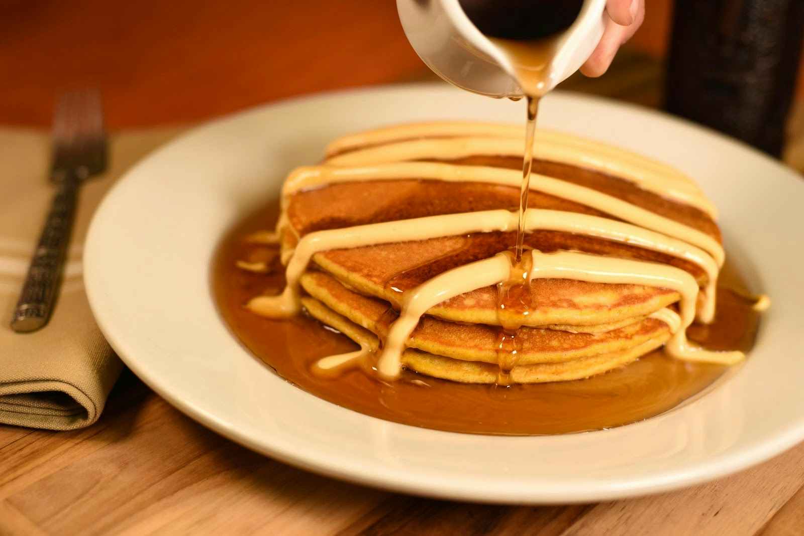 A stack of pumpkin pancakes with frosting and syrup drizzled over