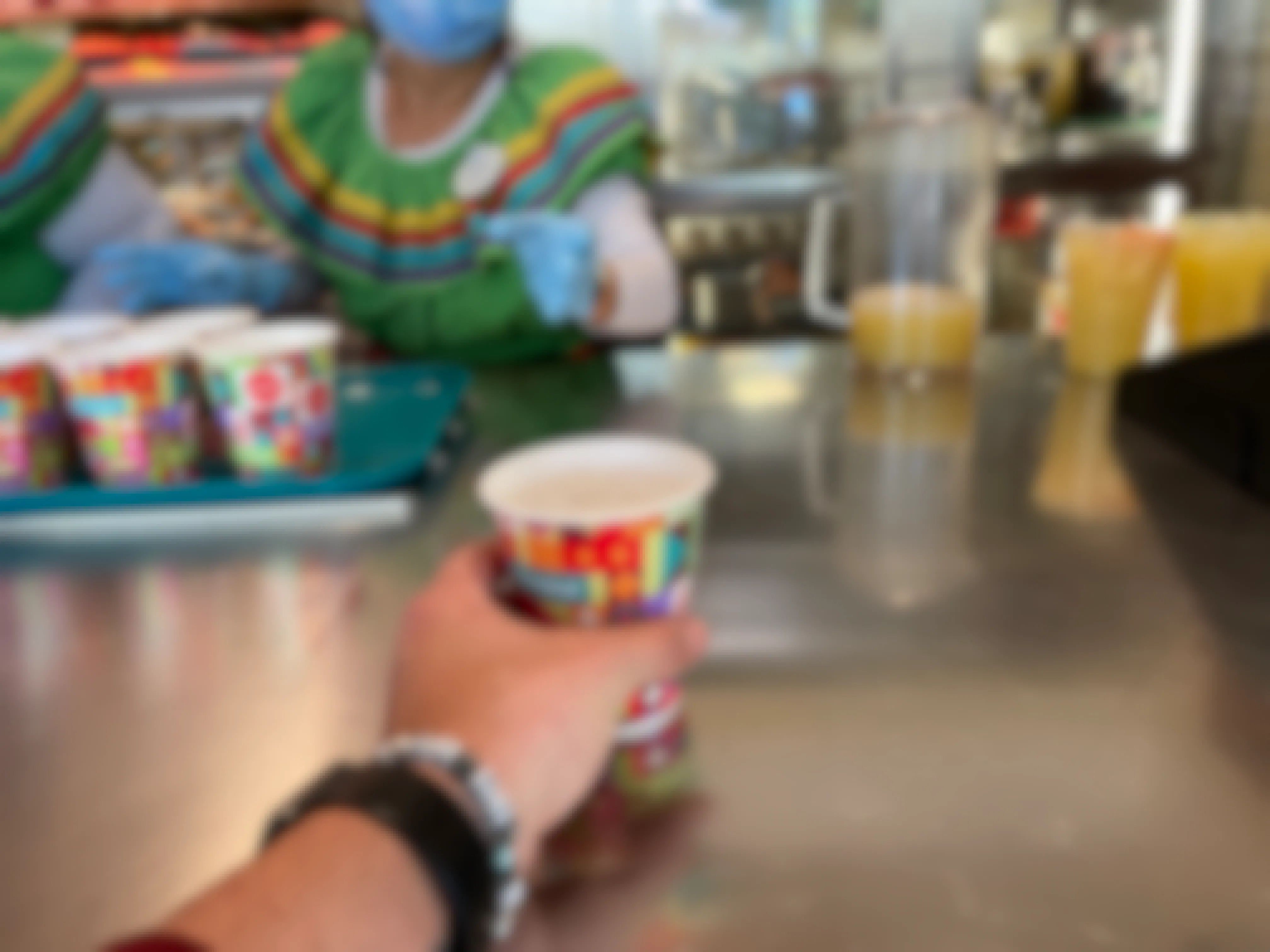 A person taking a free water cup from a counter inside a restaurant at Disneyland.