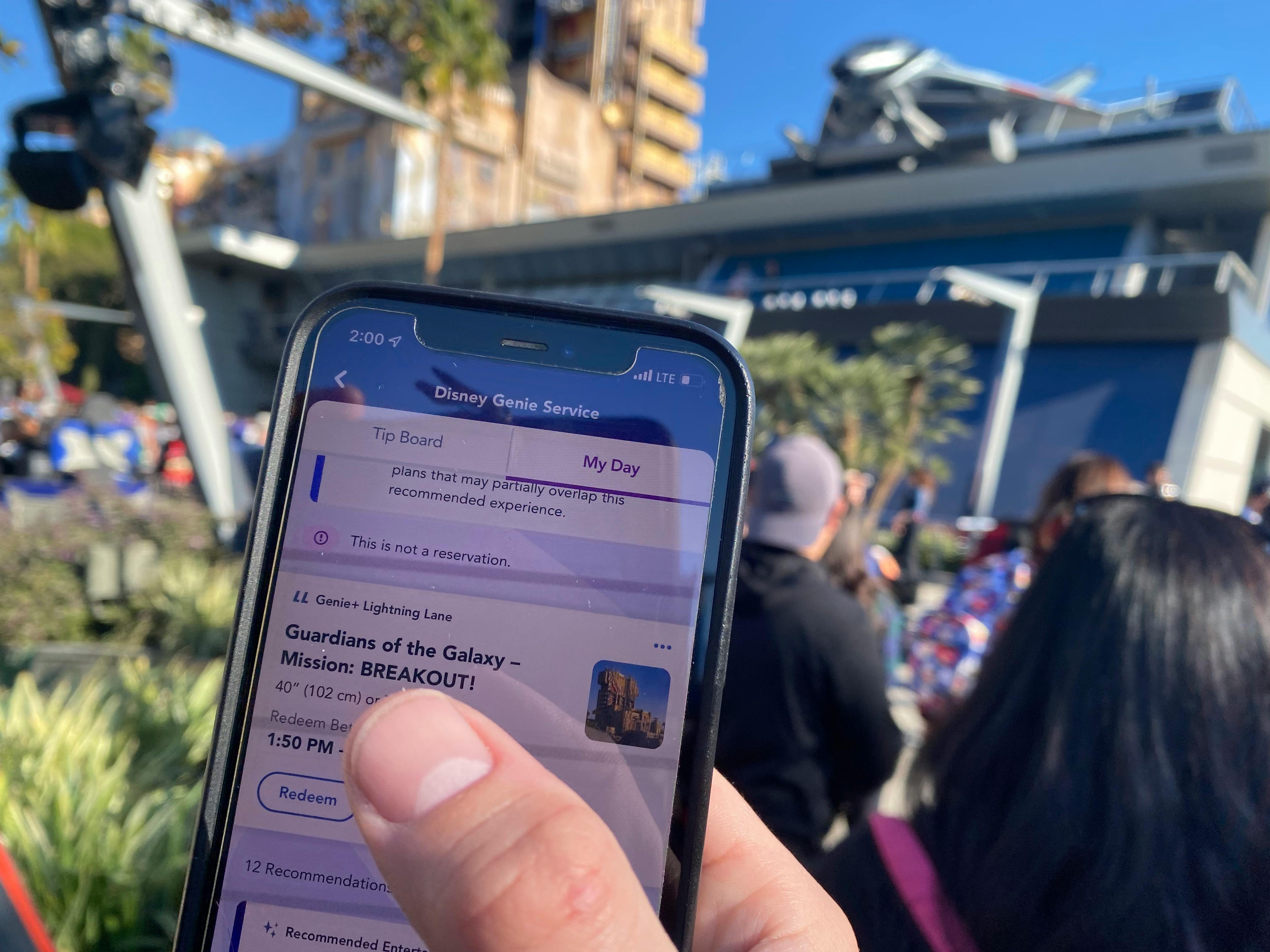 Holding phone with the Disneyland app showing Lightning Lane booking