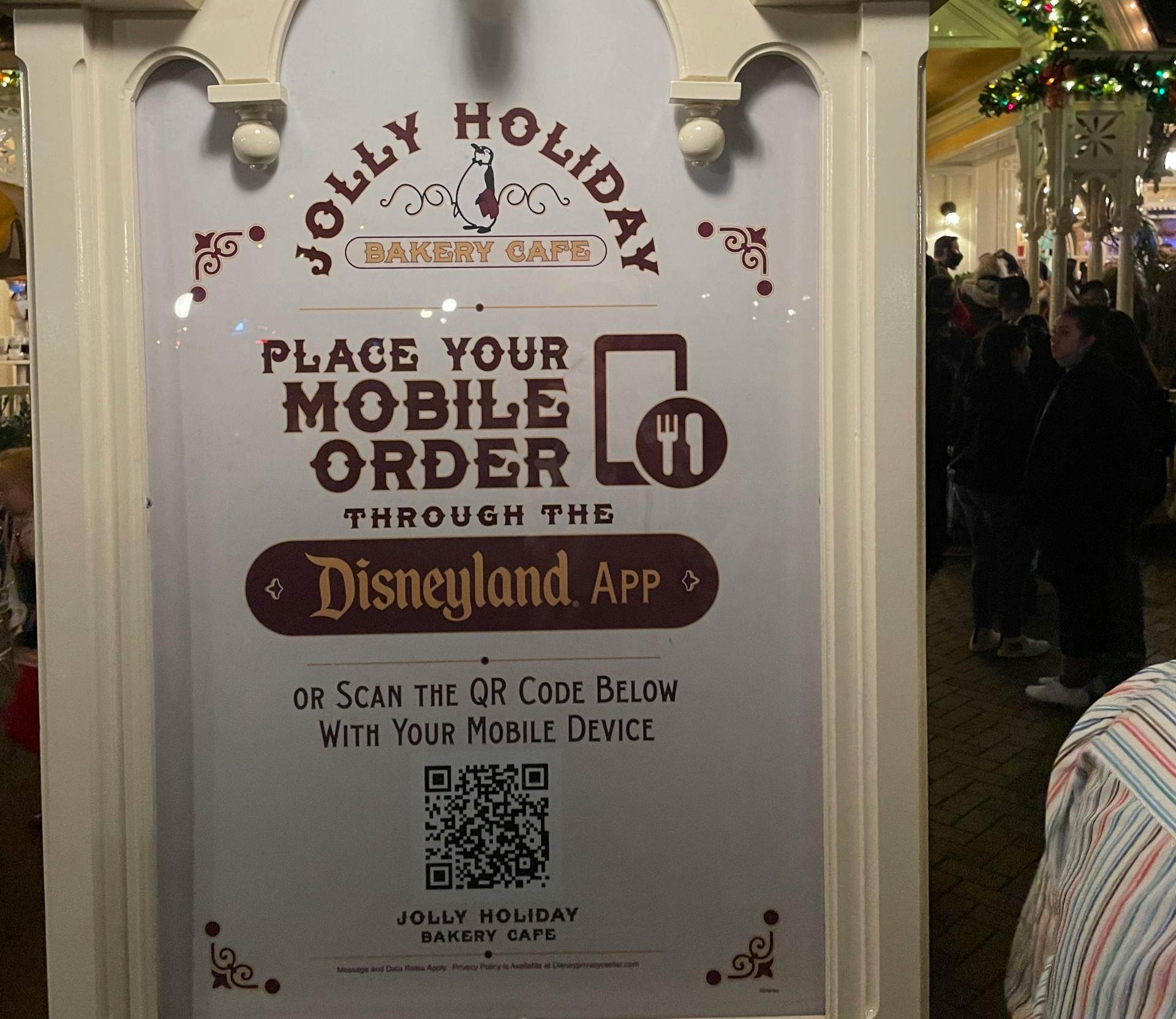 Disneyland's Jolly Holiday Bakery Cafe restaurant sign with mobile ordering instructions.