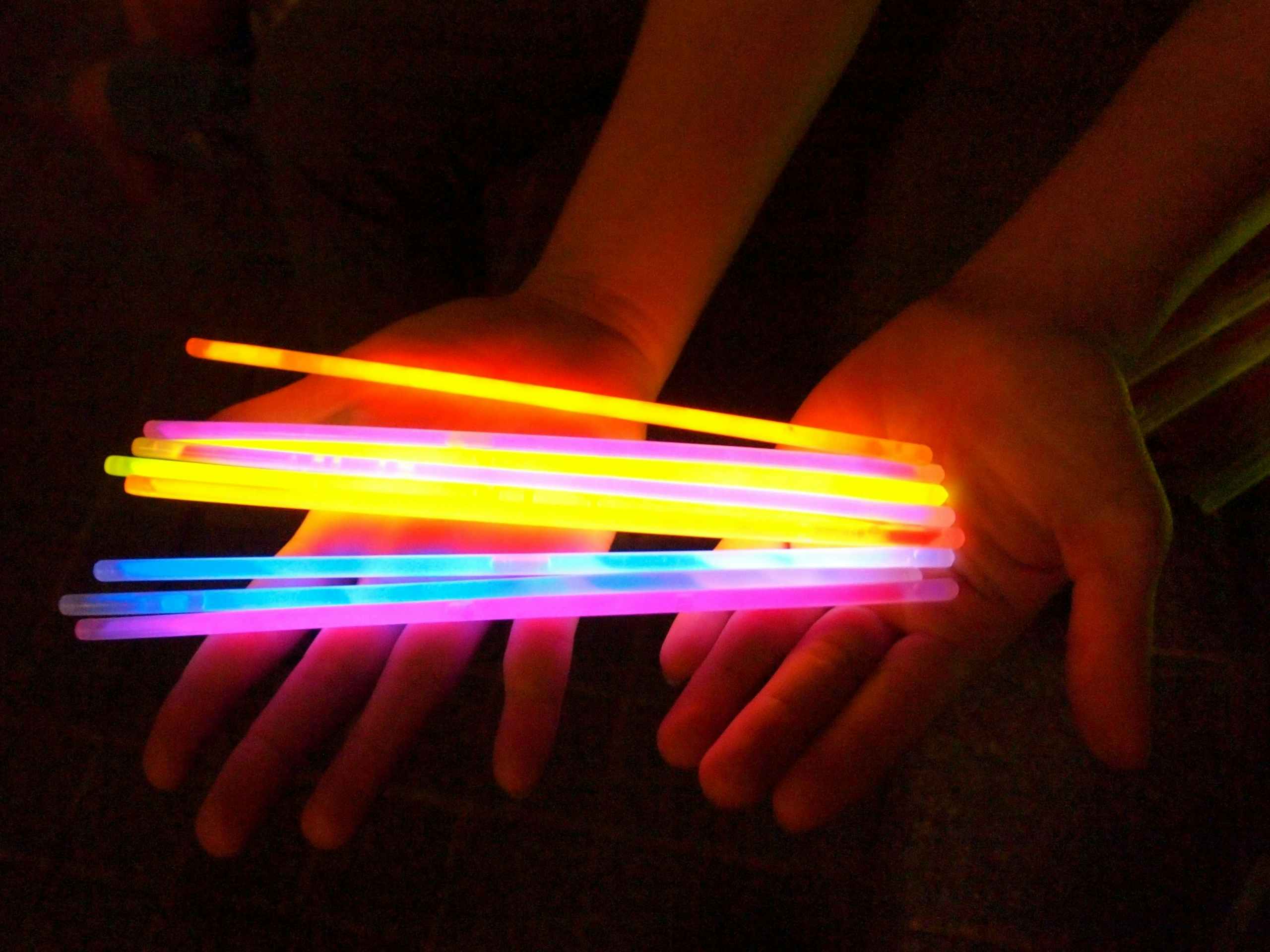 a person holding a variety of multi-colored glow sticks in the dark