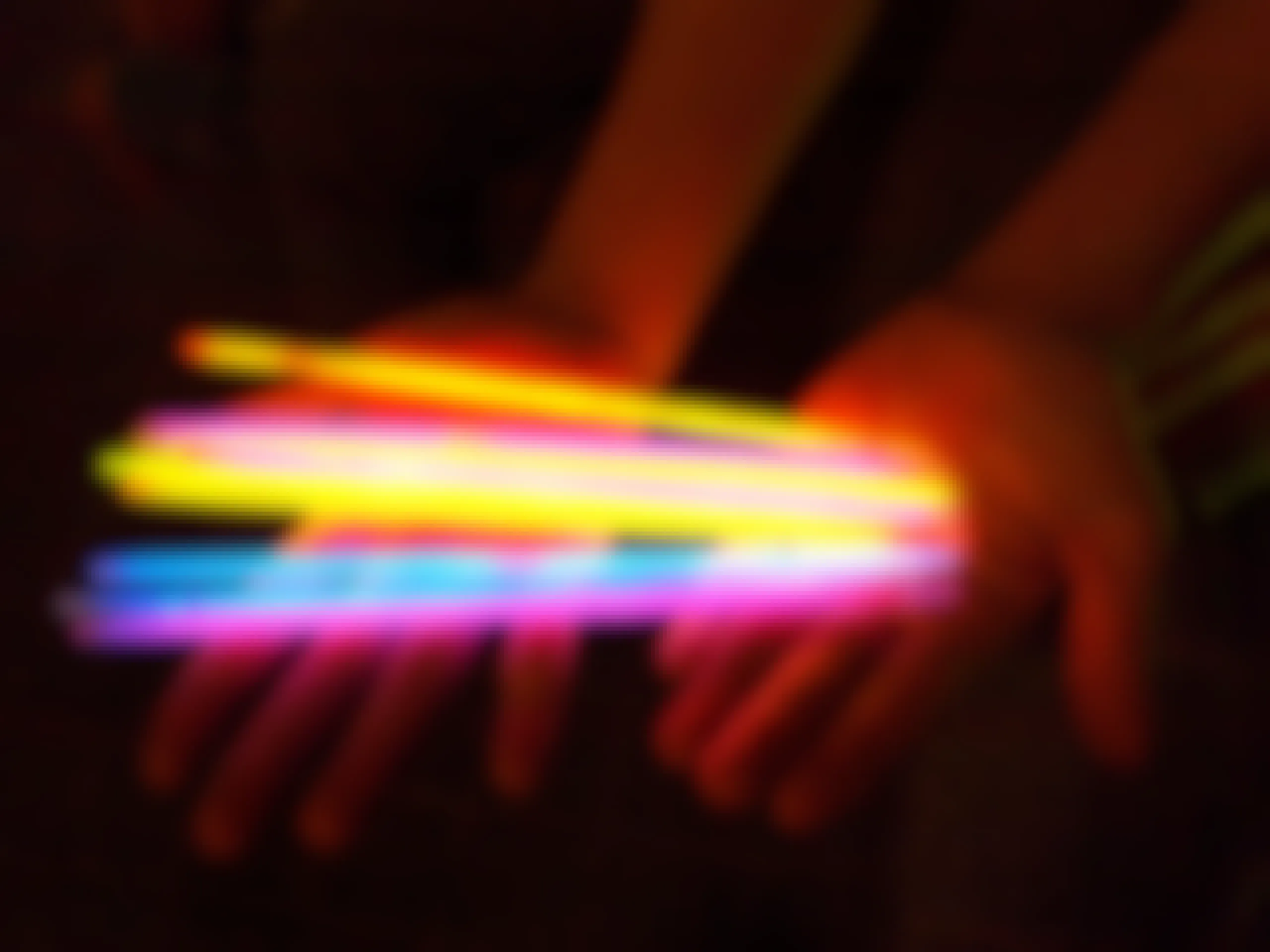 a person holding a variety of multi-colored glow sticks in the dark