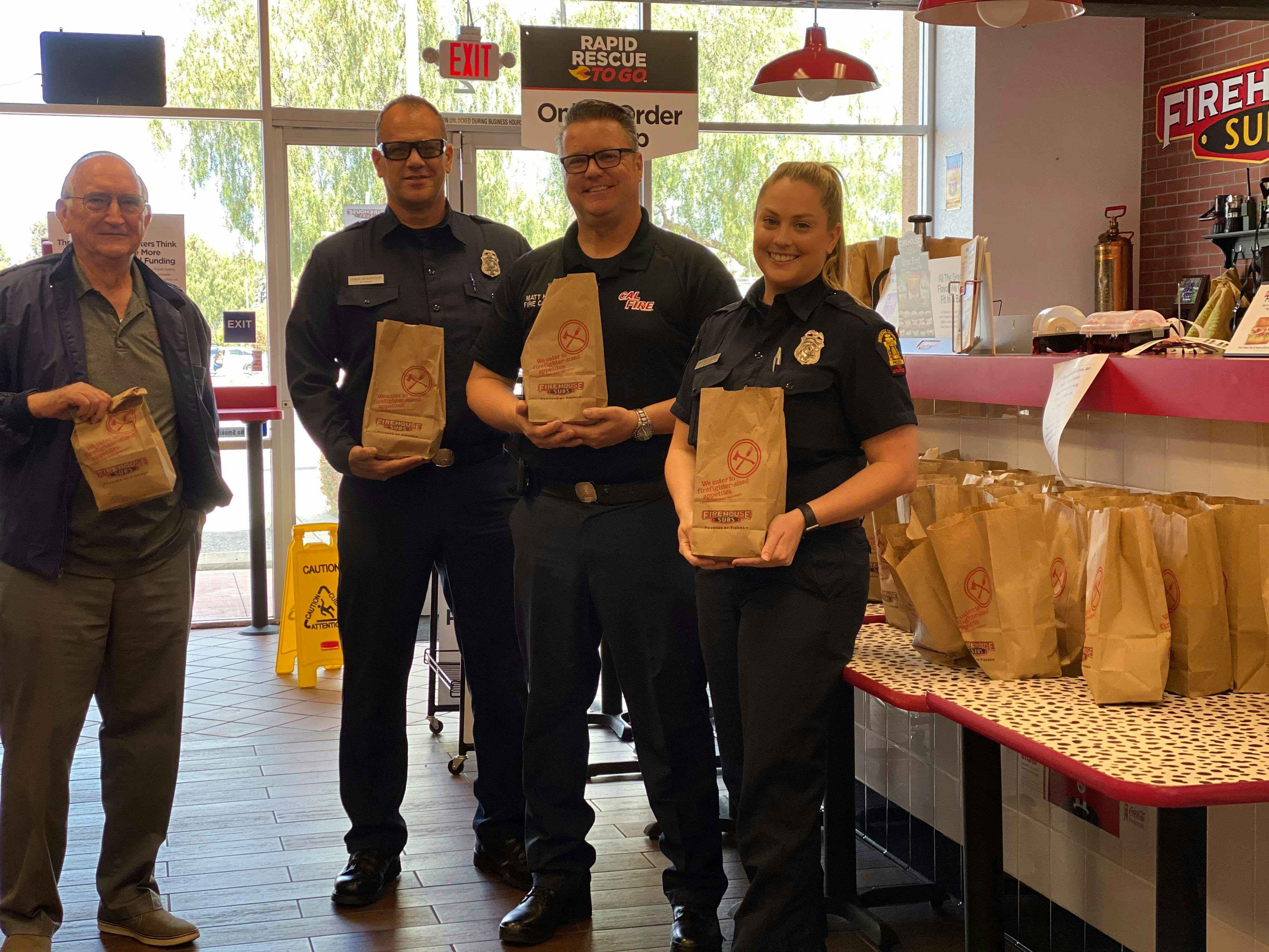 people holding firehouse subs bags