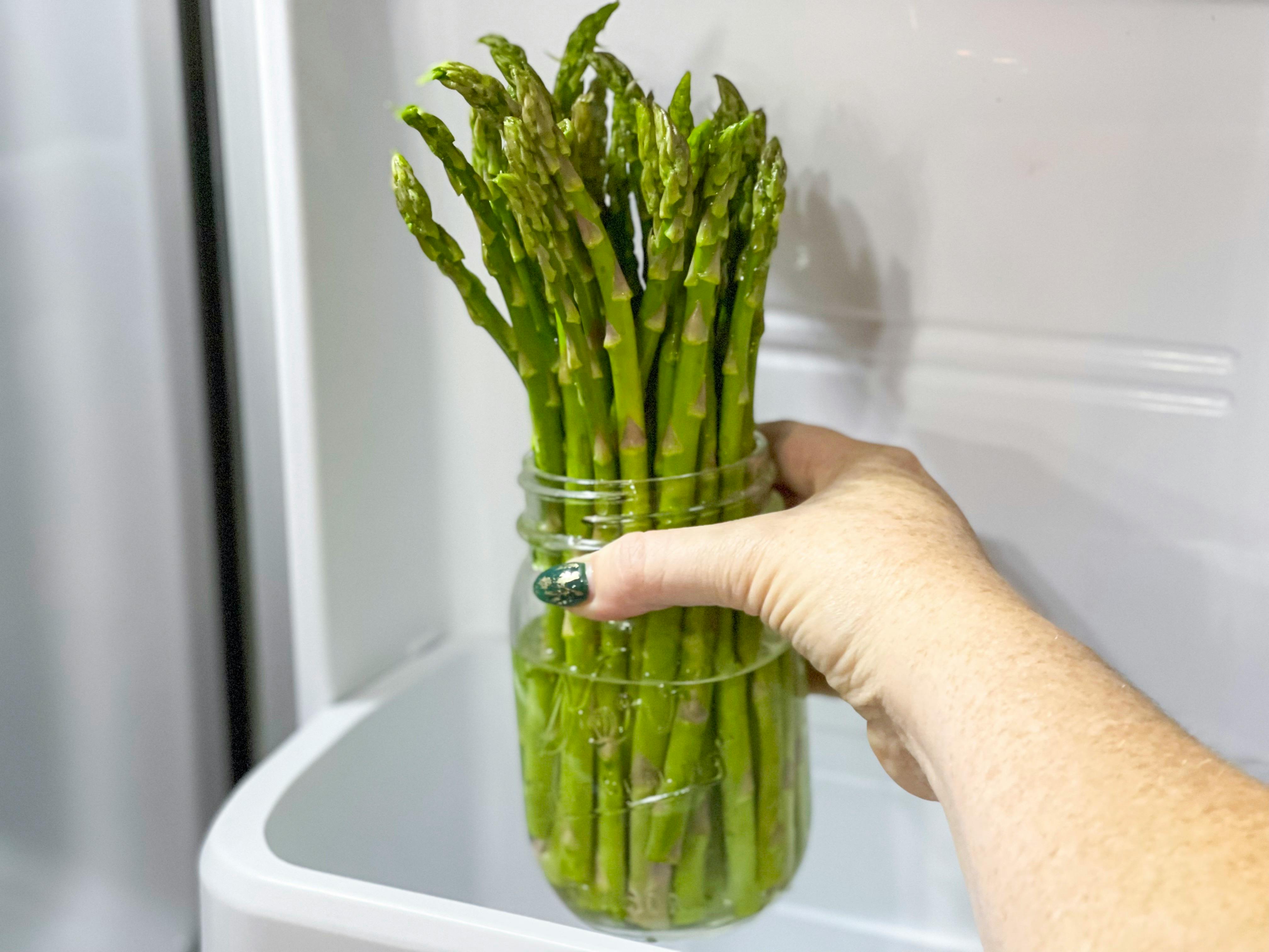 asparagus in mason jar being placed in fridge