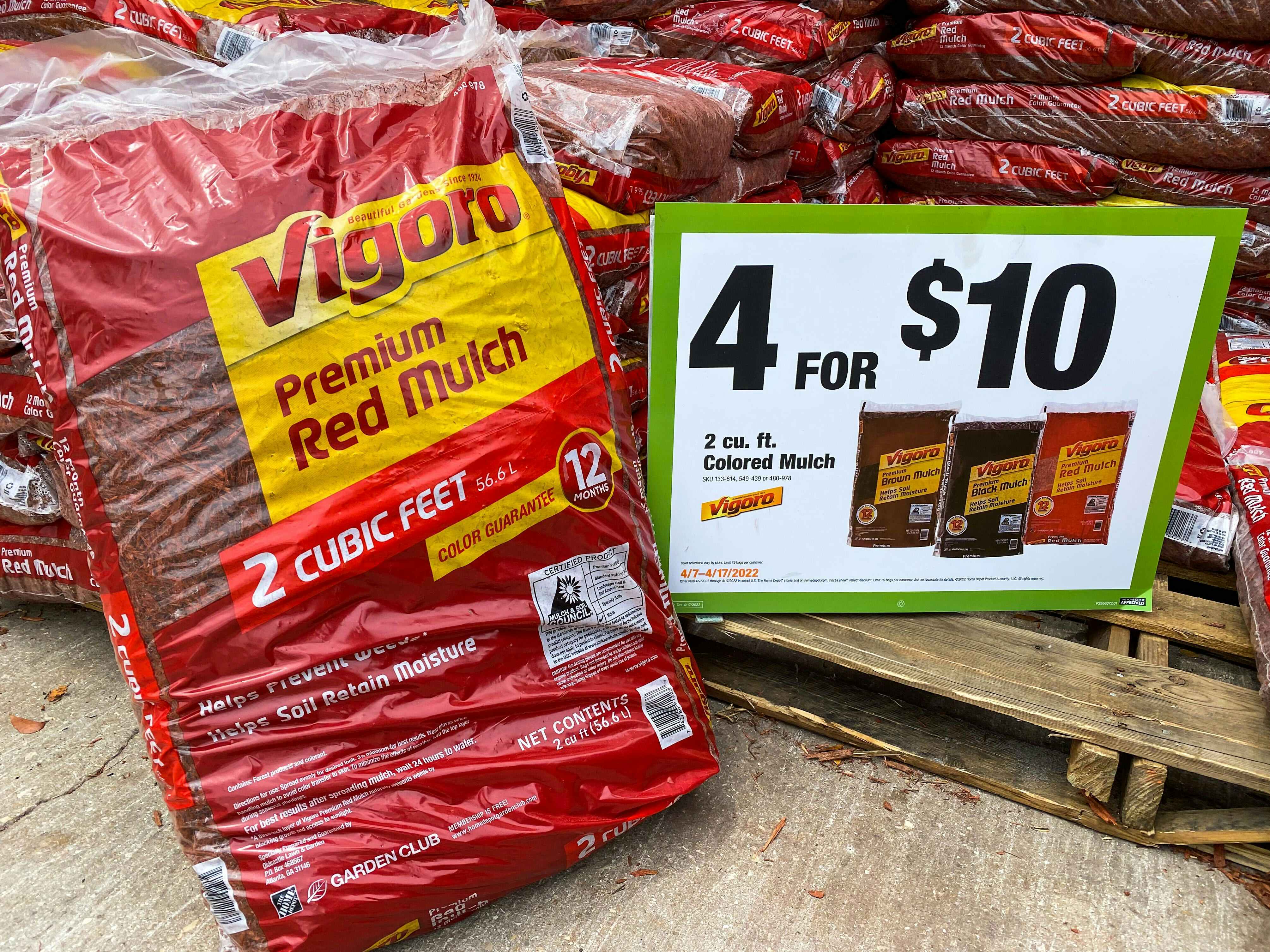  A bag of vigoro red mulch next to a 4 for $10 sign at Home Depot