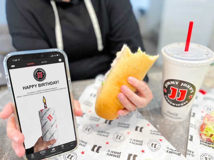 cellphone with birthday app and woman holding sandwich 