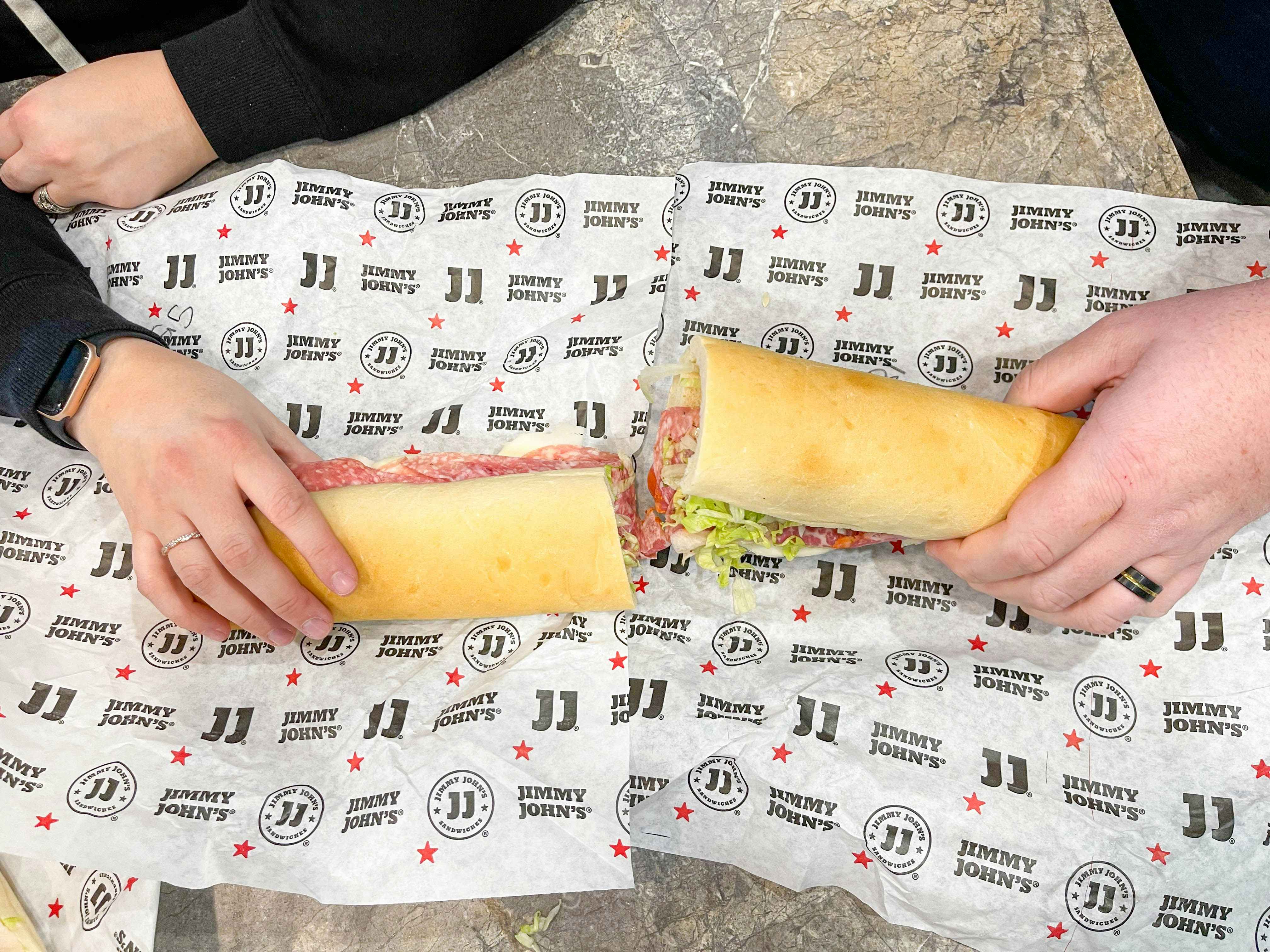 two hands holding cut giant sandwich 