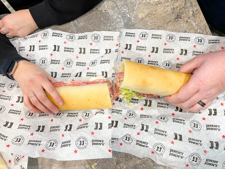 two hands holding cut giant sandwich 