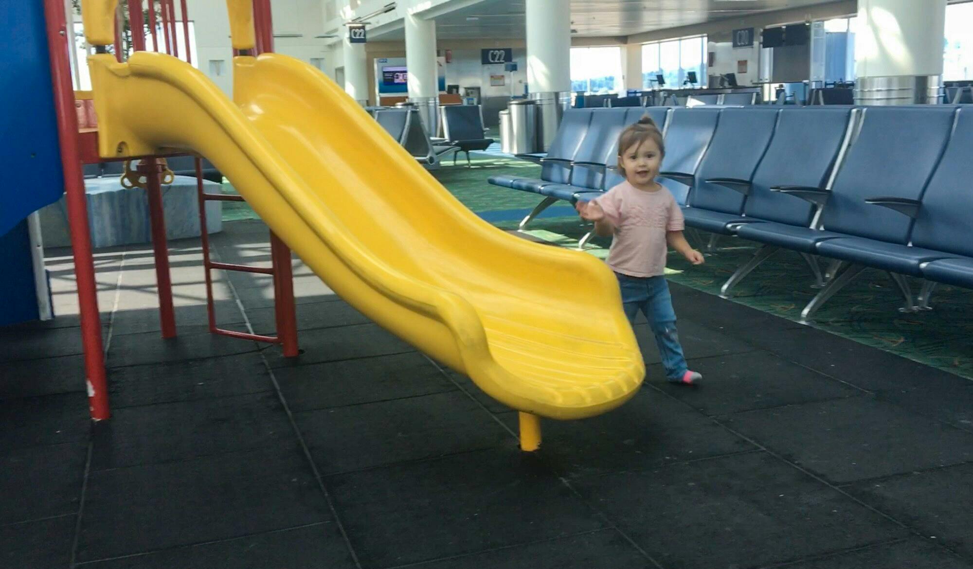 a small child walking next to a slide in an airport