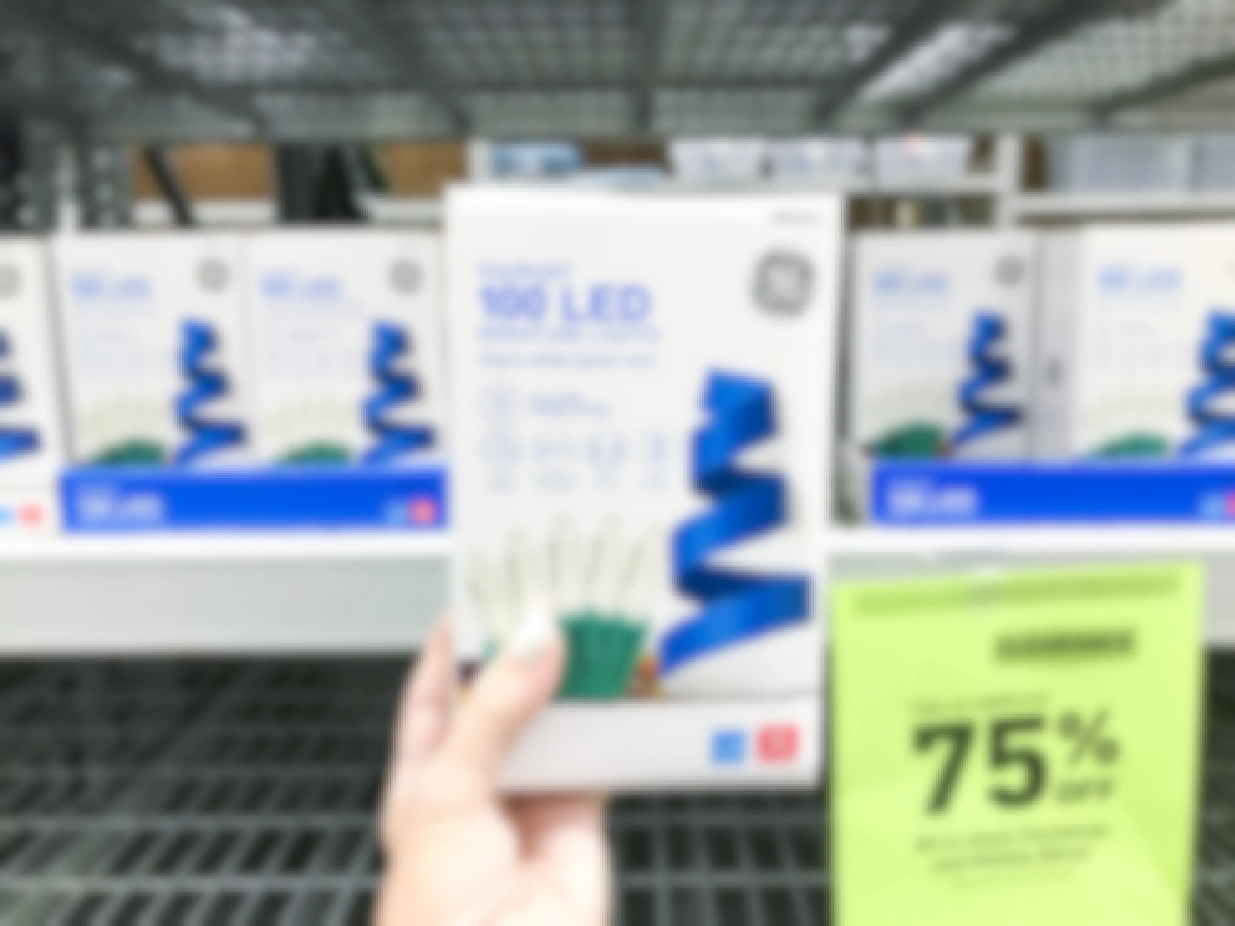 A person holding a box of StayBright LED miniature Christmas lights at Lowes.