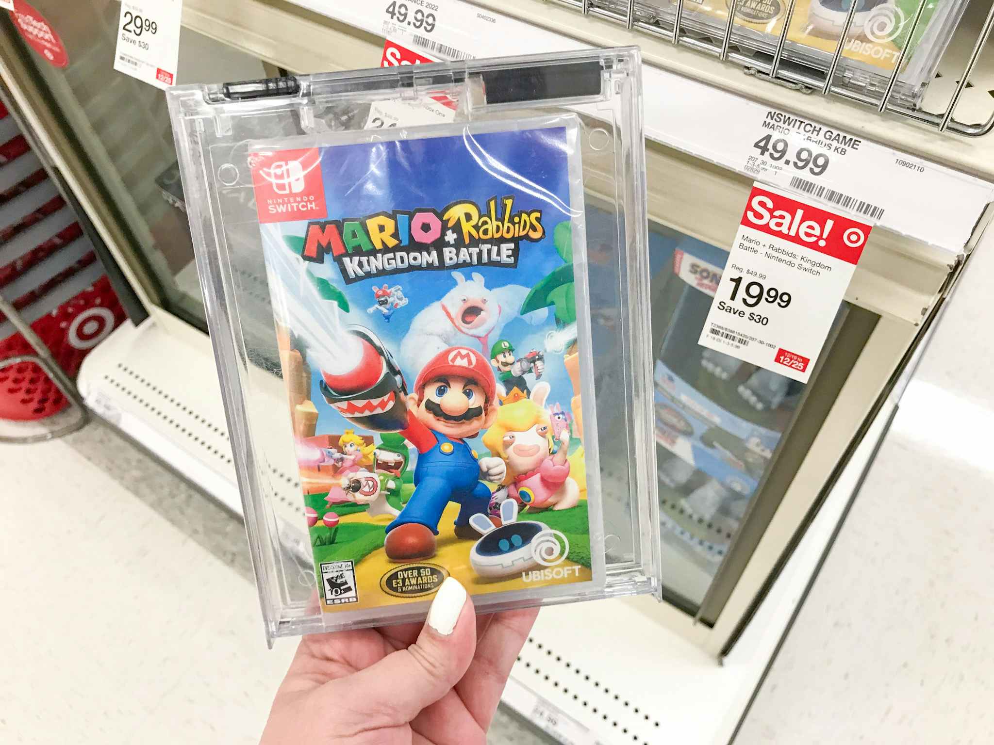 A person's hand holding a Mario game near a sale tag inside target.