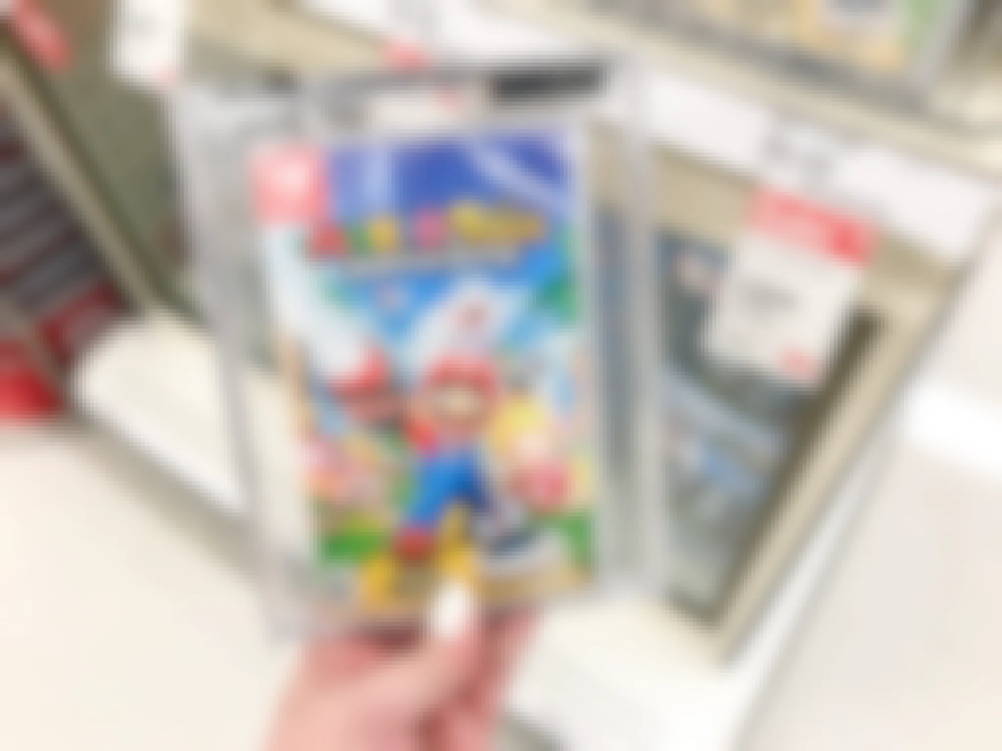 A person's hand holding a Mario game near a sale tag inside target.