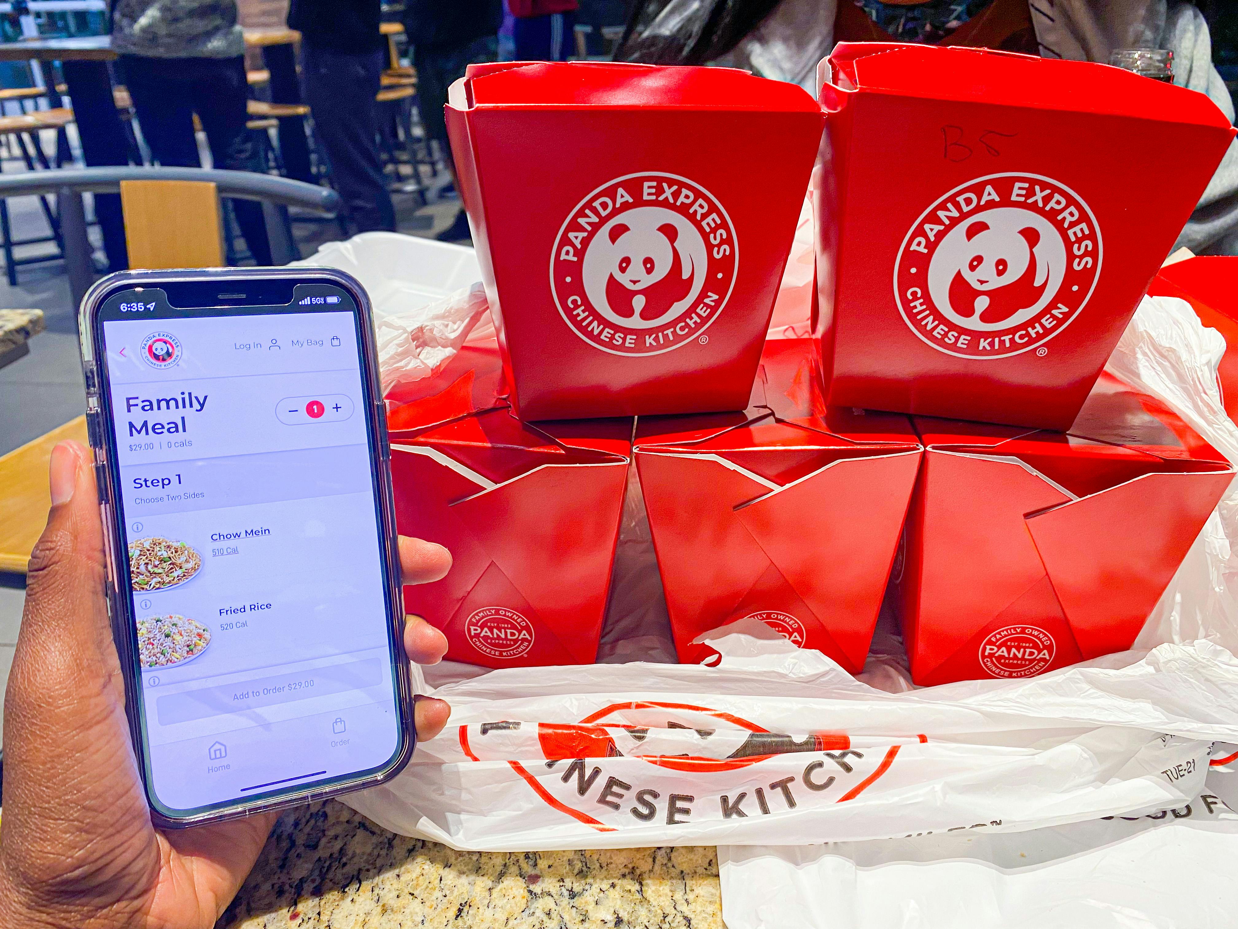 someone holding a phone next to a family Panda Express meal