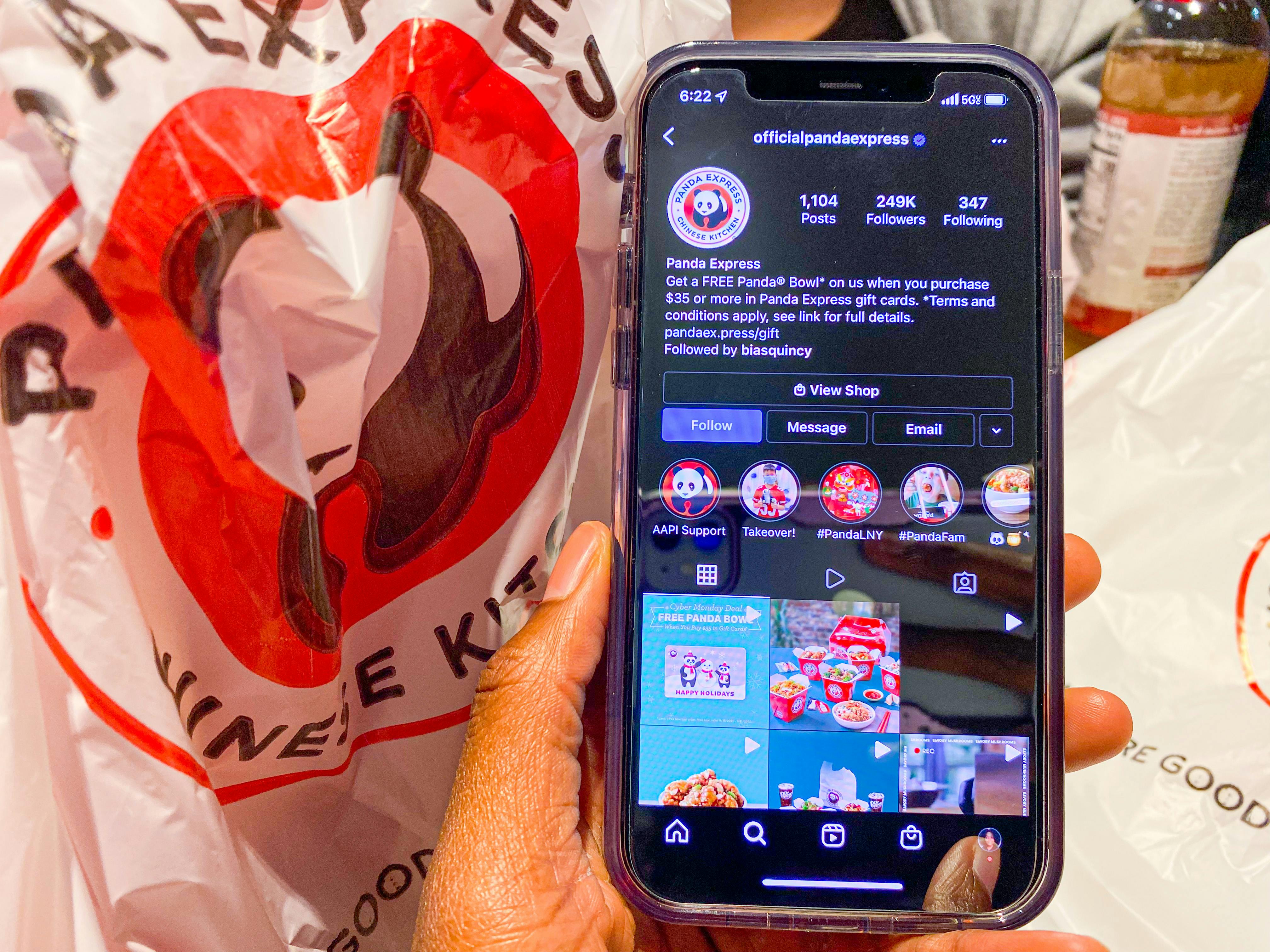 a phone held in hand next to a Panda Express bag