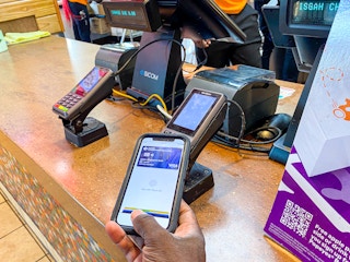 Person using apple pay at Popeyes restaurant counter
