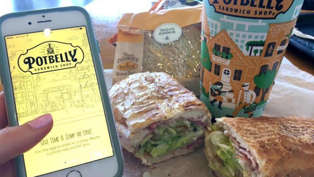 someone holding phone with potbelly app next to sandwich