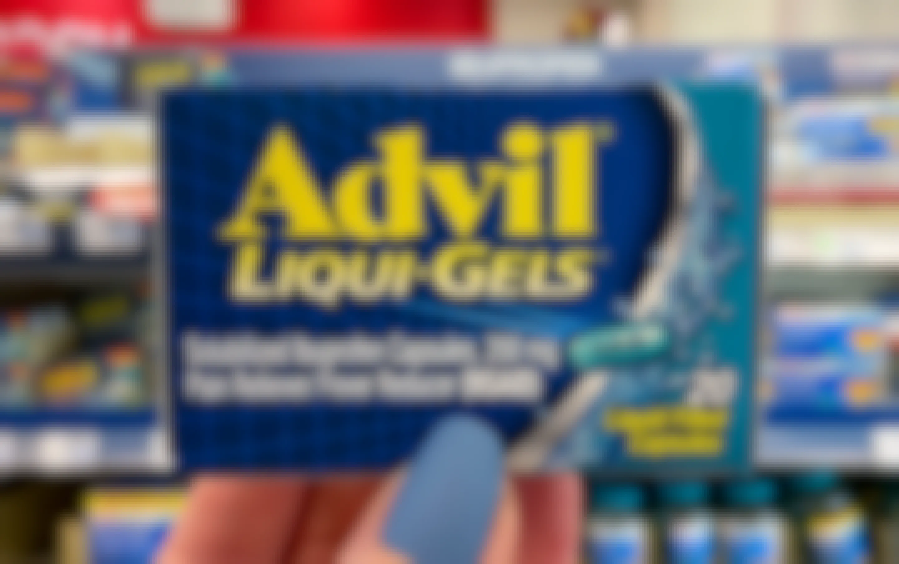 A person's hand holding up a box of advil liquid gels in store.