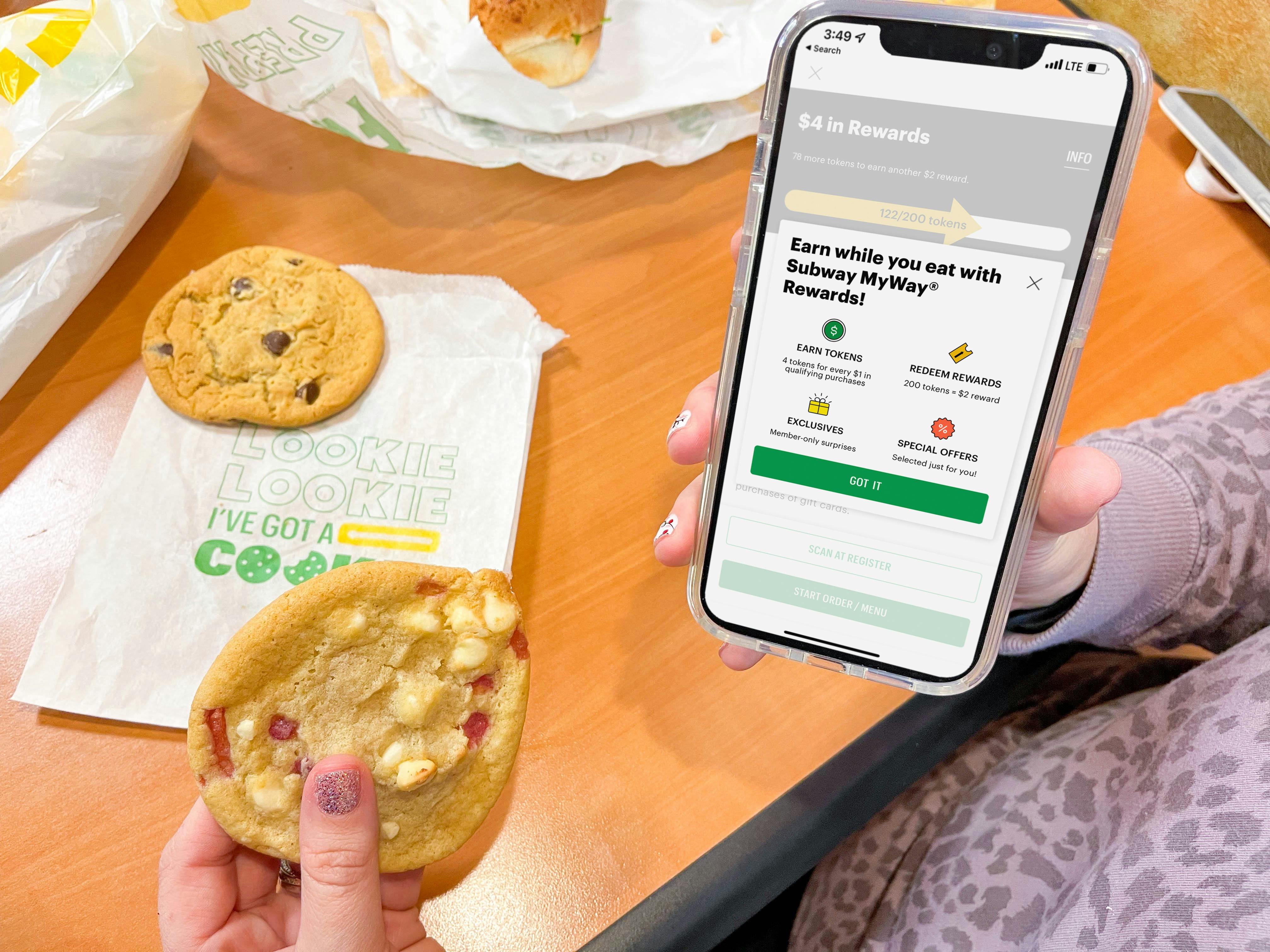 woman holding cellphone with subway app and cookie