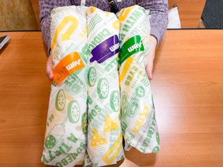 woman holding 3 footlong subs