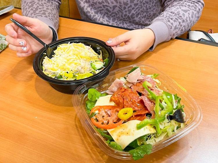 woman eating no bready bowl and salad at subway