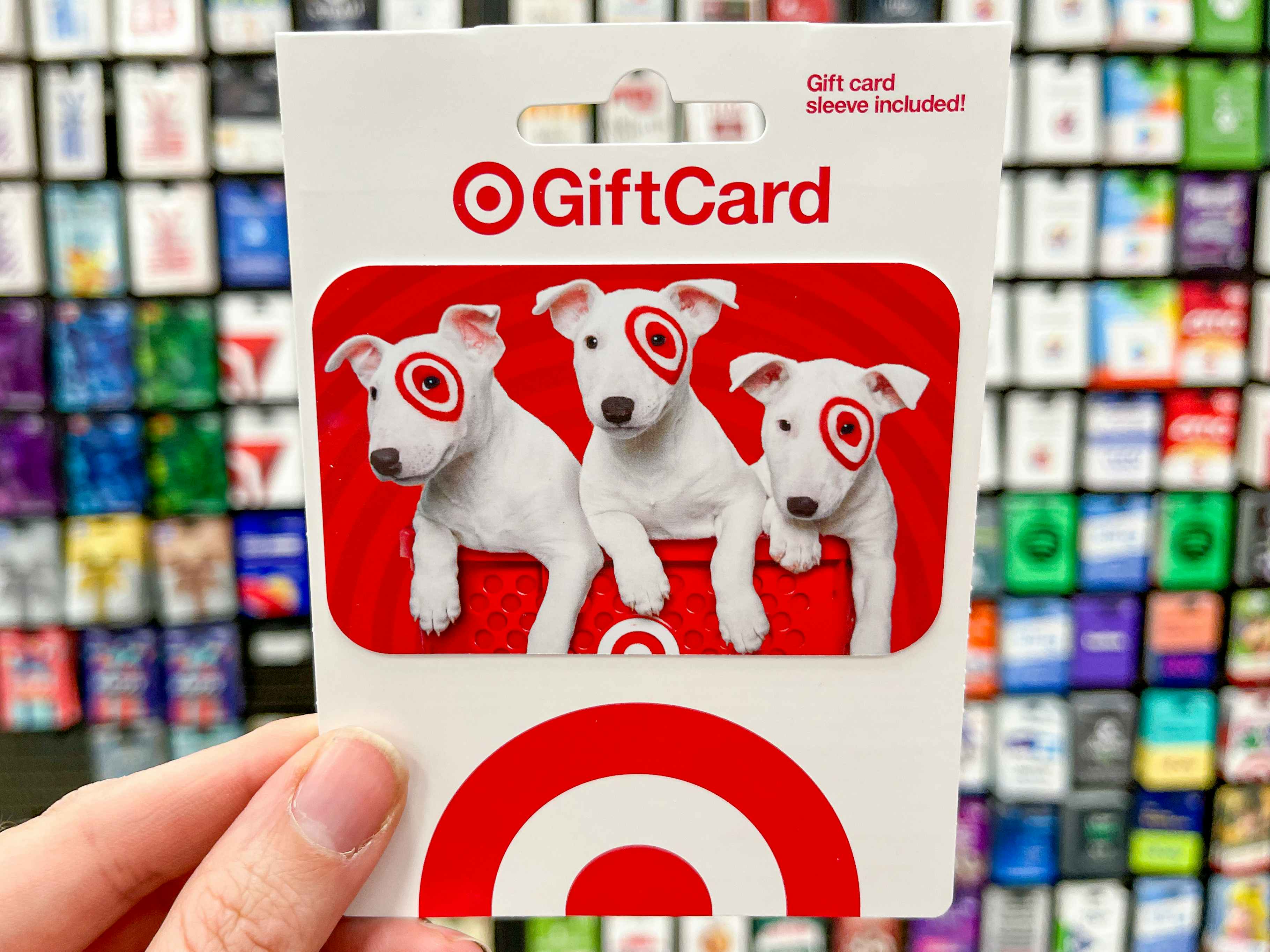 A Target gift card held in front of the wall of gift cards in Target