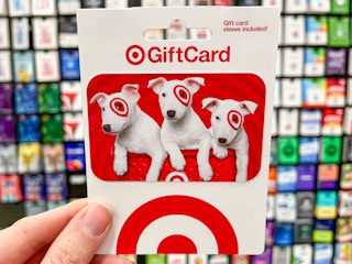 A Target gift card held in front of the wall of gift cards in Target