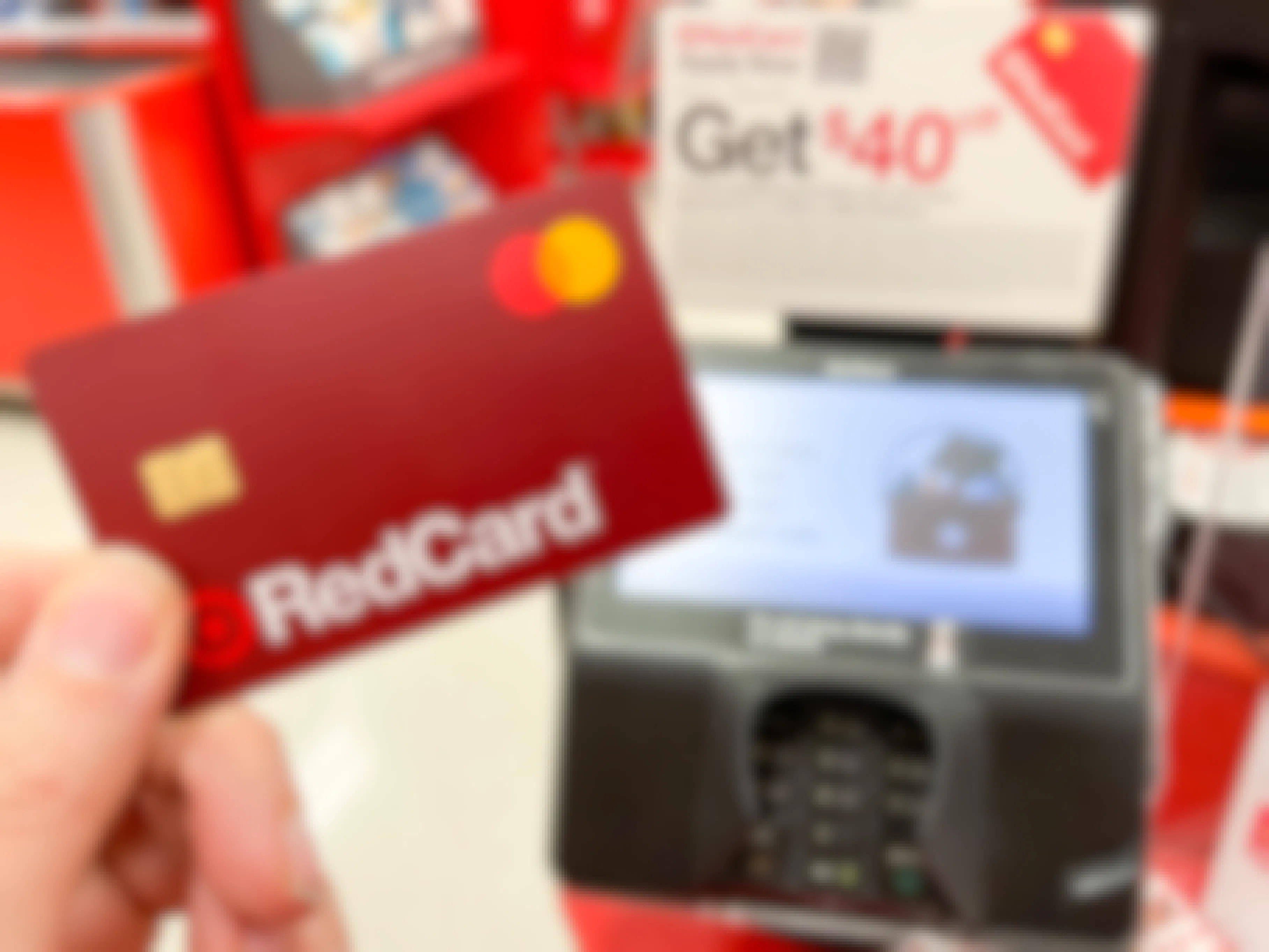 A Target RedCard being held next to a credit card reader at Target checkout.
