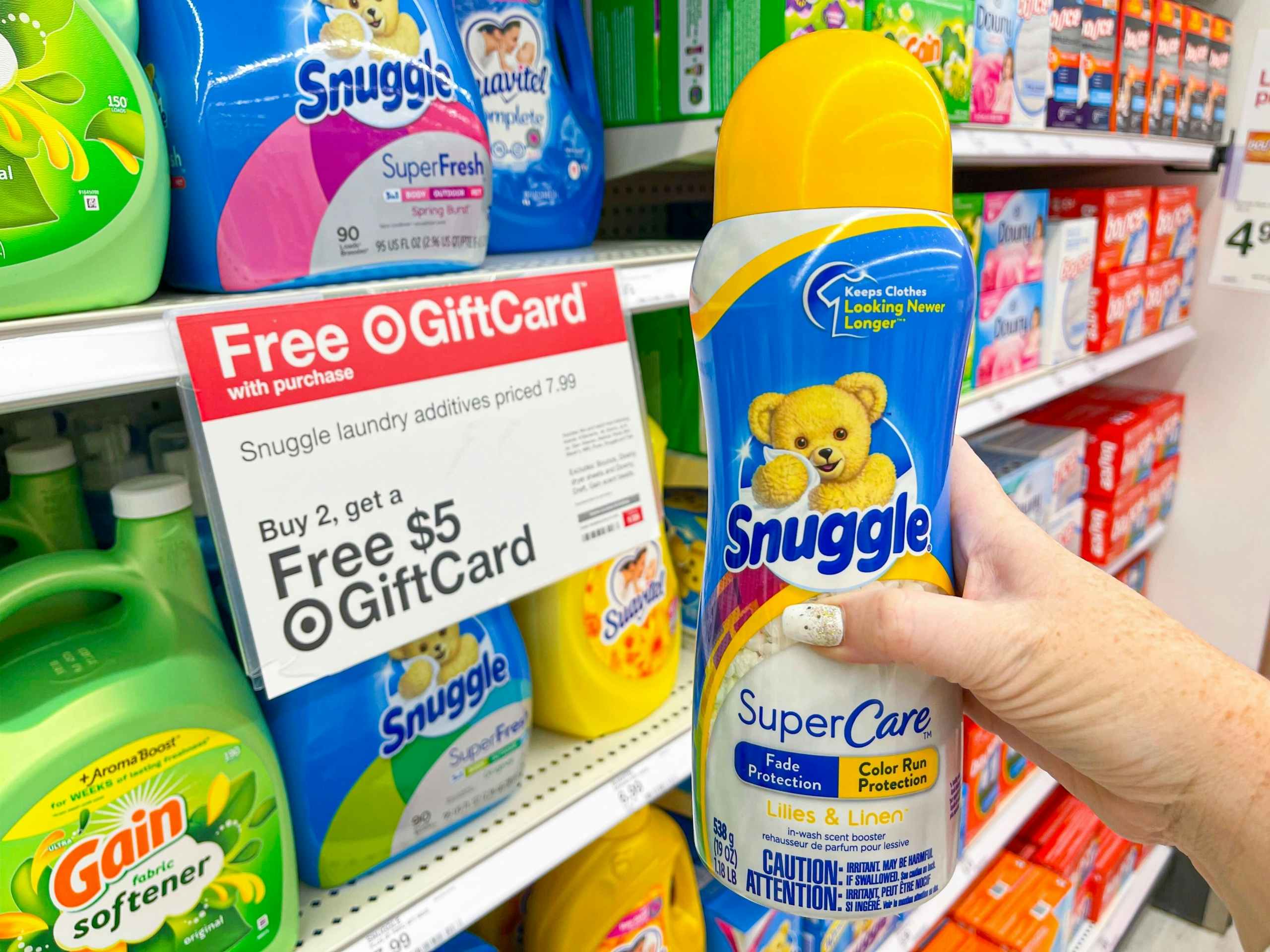hand holding snuggle scent booster in front of target laundry promotion sign