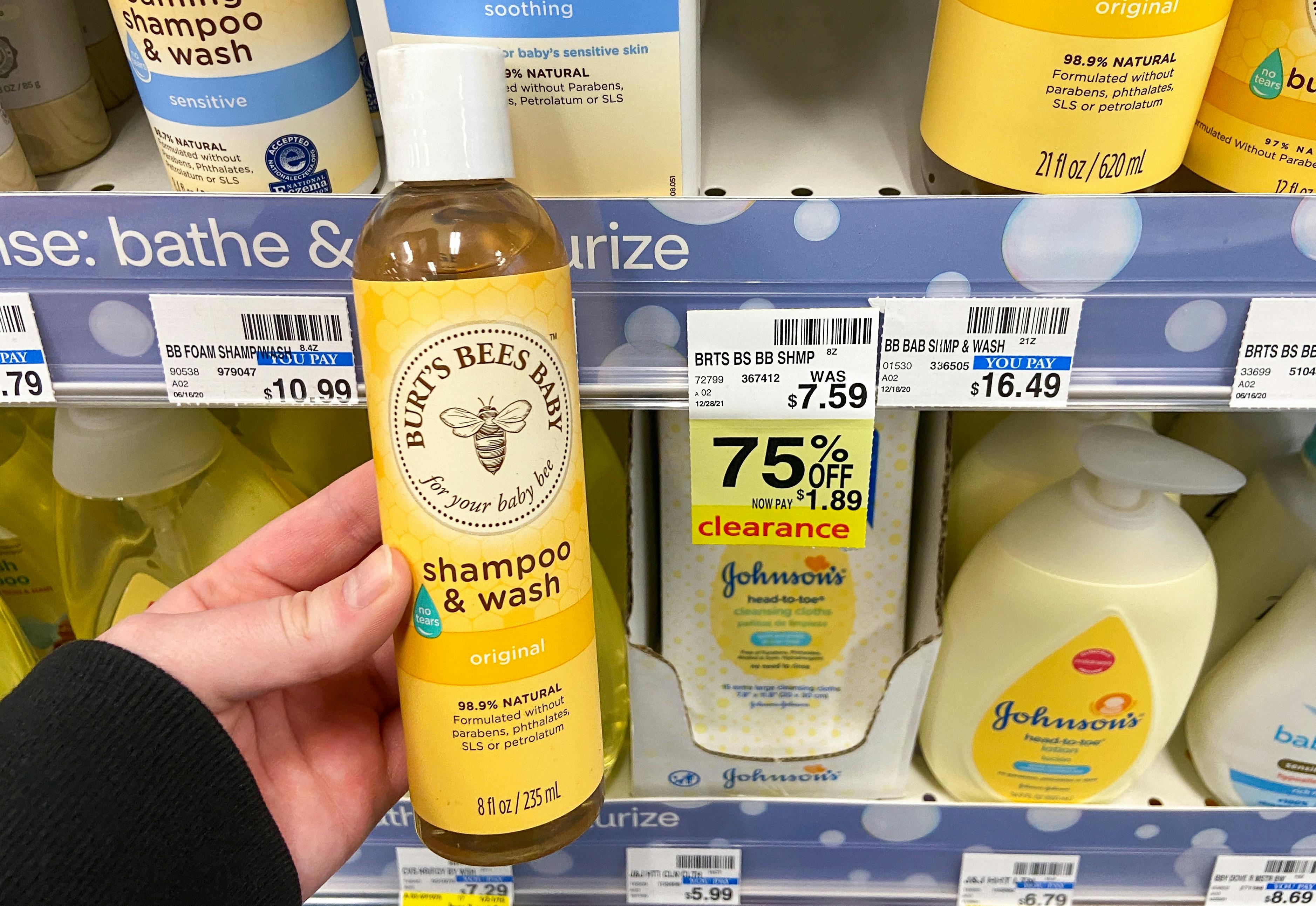 A person's hand holding a bottle of Burt's Bees Baby shampoo & Wash in front of a shelf at CVS.