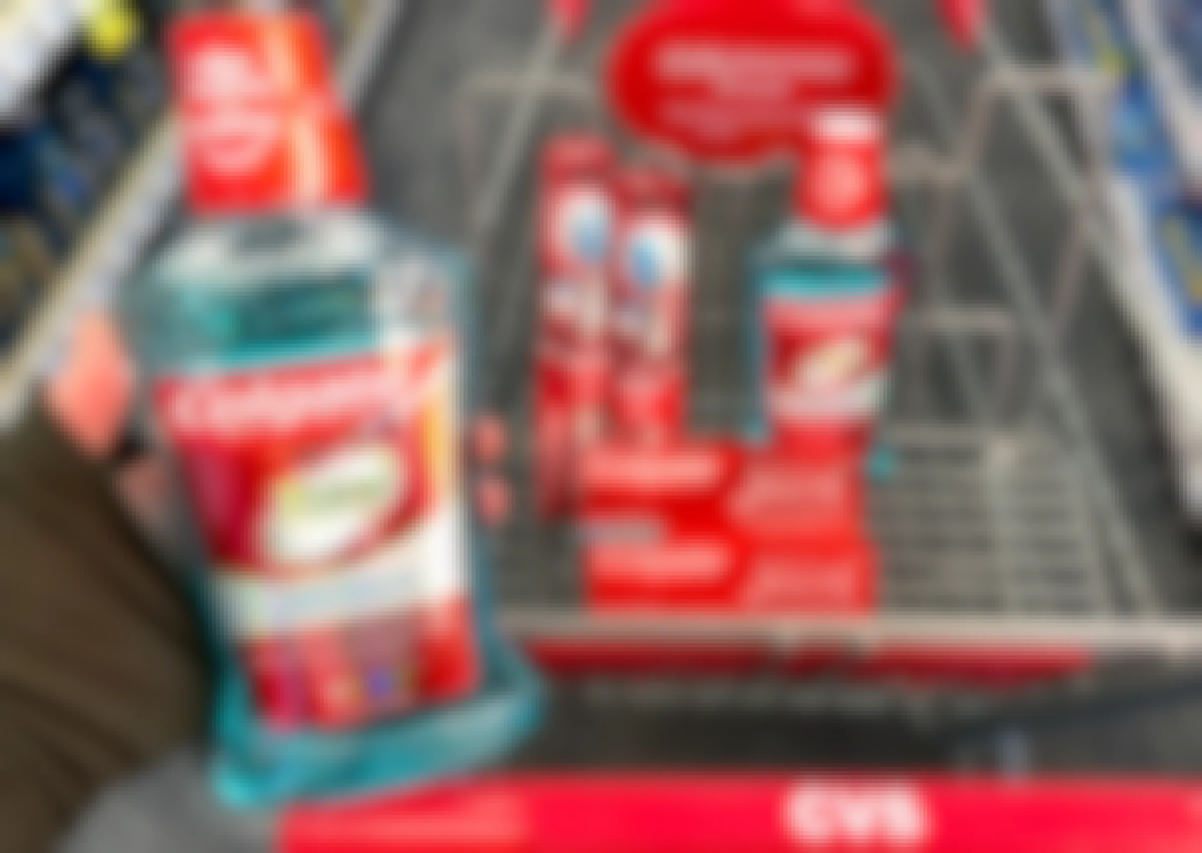 A person's hand holding a bottle of Colgate Total mouthwash above a CVS shopping cart with more Colgate mouthwash, Colgate Optic White toothpaste, and Colgate toothbrushes in the basket.