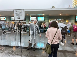 A Disney employee directing patrons to the Early Entry line for guests of participating hotels at the entrance of Disney Hollywood.