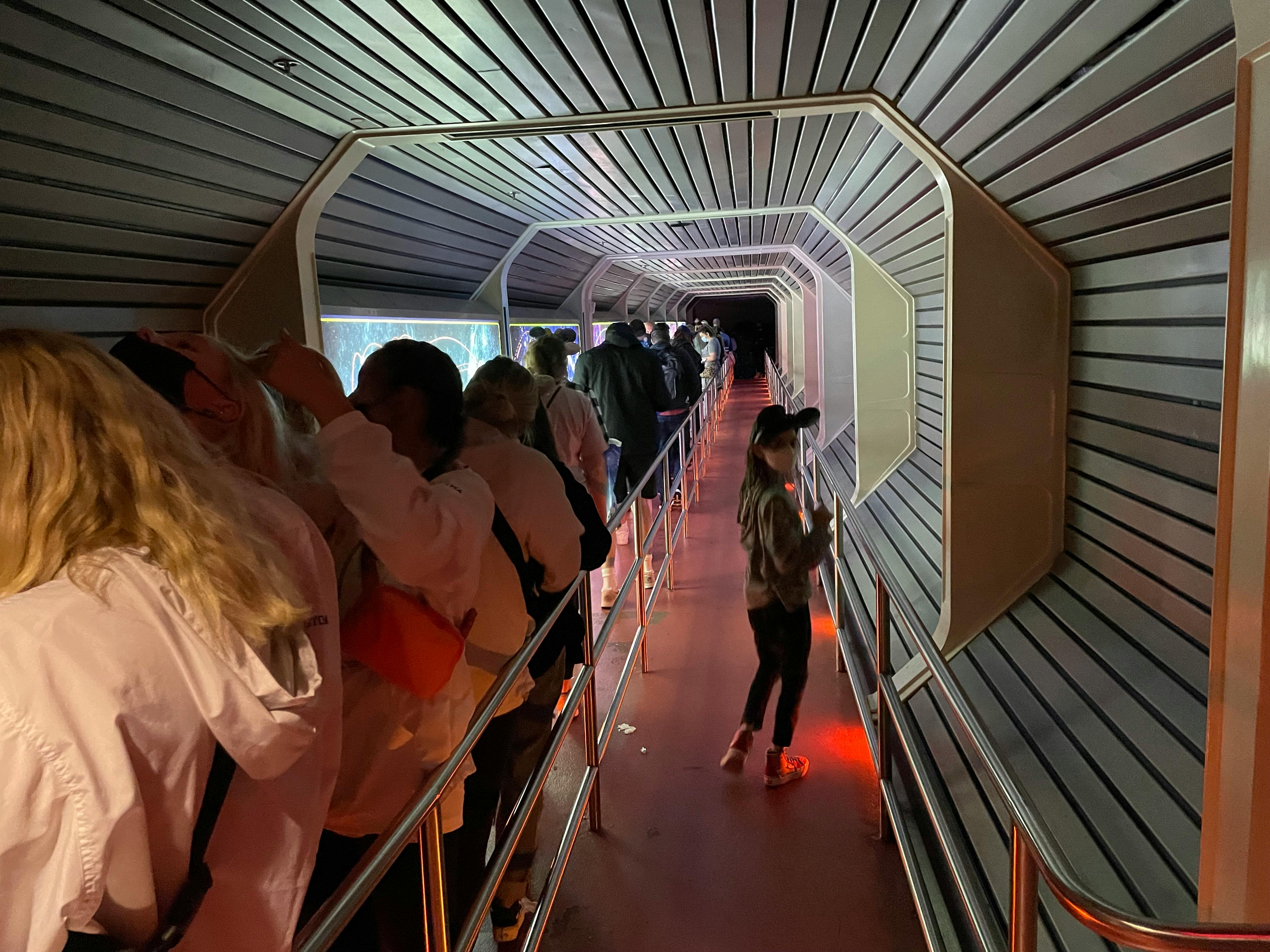 A child in the Lightning Lane at Space Mountain while crowds fill the standby lane.