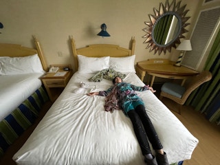 Girl flops down on a hotel room bed