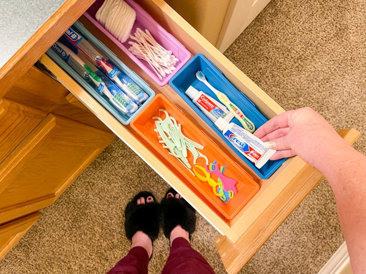 someone putting toothpaste in basket in drawer