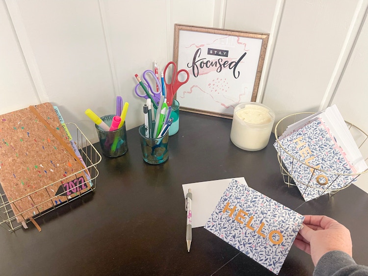 someone putting card on desk with organized baskets