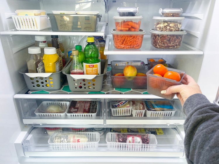 someone putting another storage basket in the refridgerator