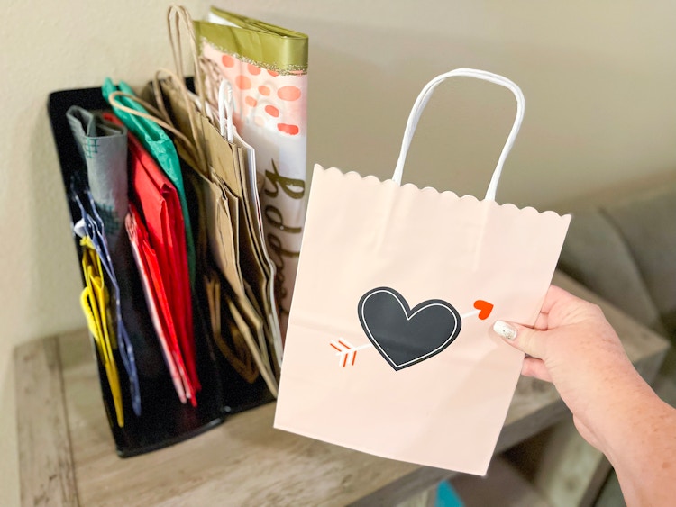 someone putting gift bag in plastic magazine rack