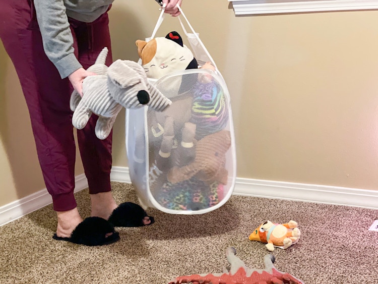 someone putting toys into laundry basket
