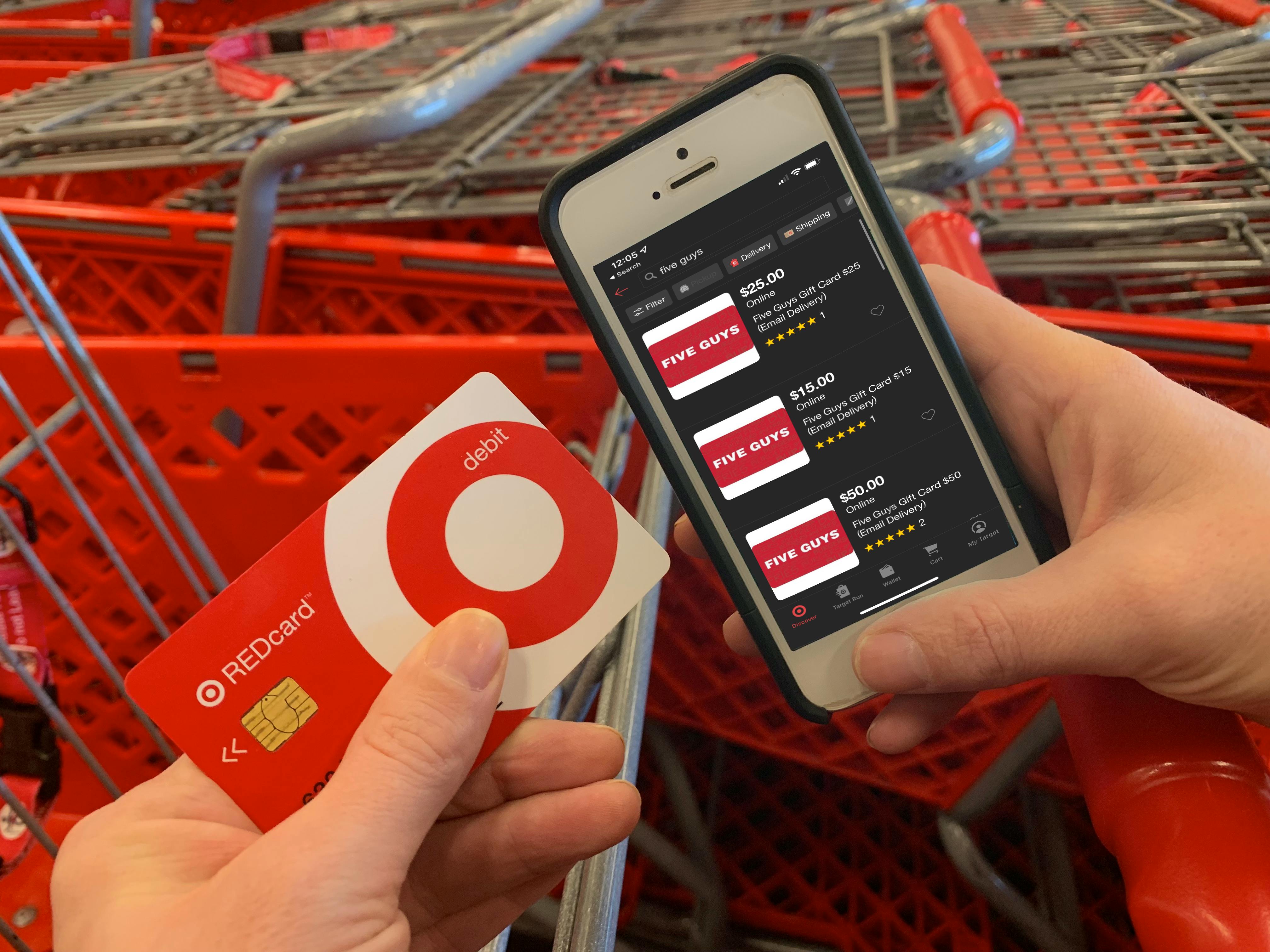 Person holding Target RedCard next to phone with Five Guys gift cards displayed on Target app