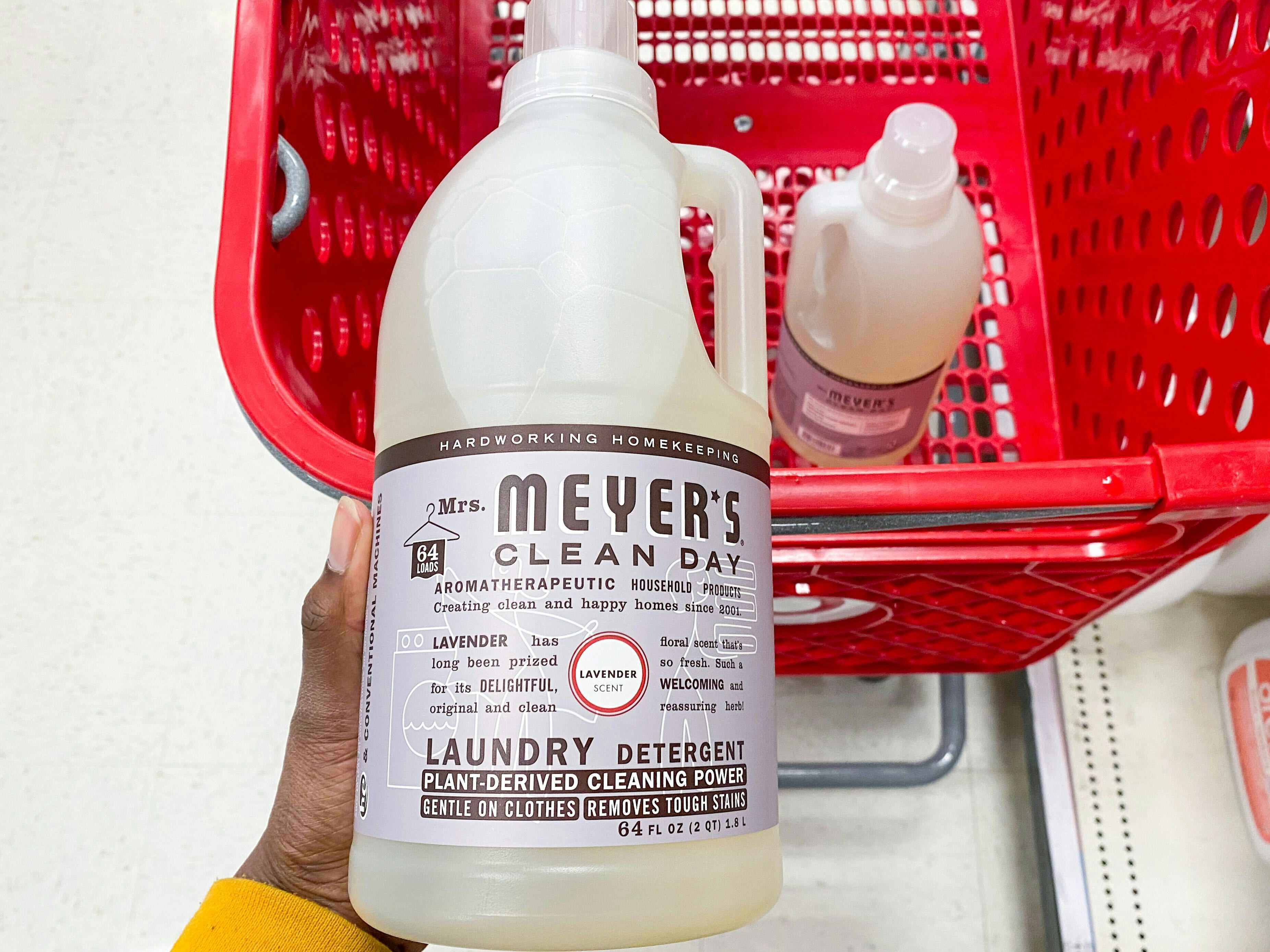 hand holding up a bottle of mrs meyers detergent over the top of a Target shopping cart