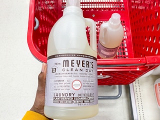 hand holding up a bottle of mrs meyers detergent over the top of a Target shopping cart