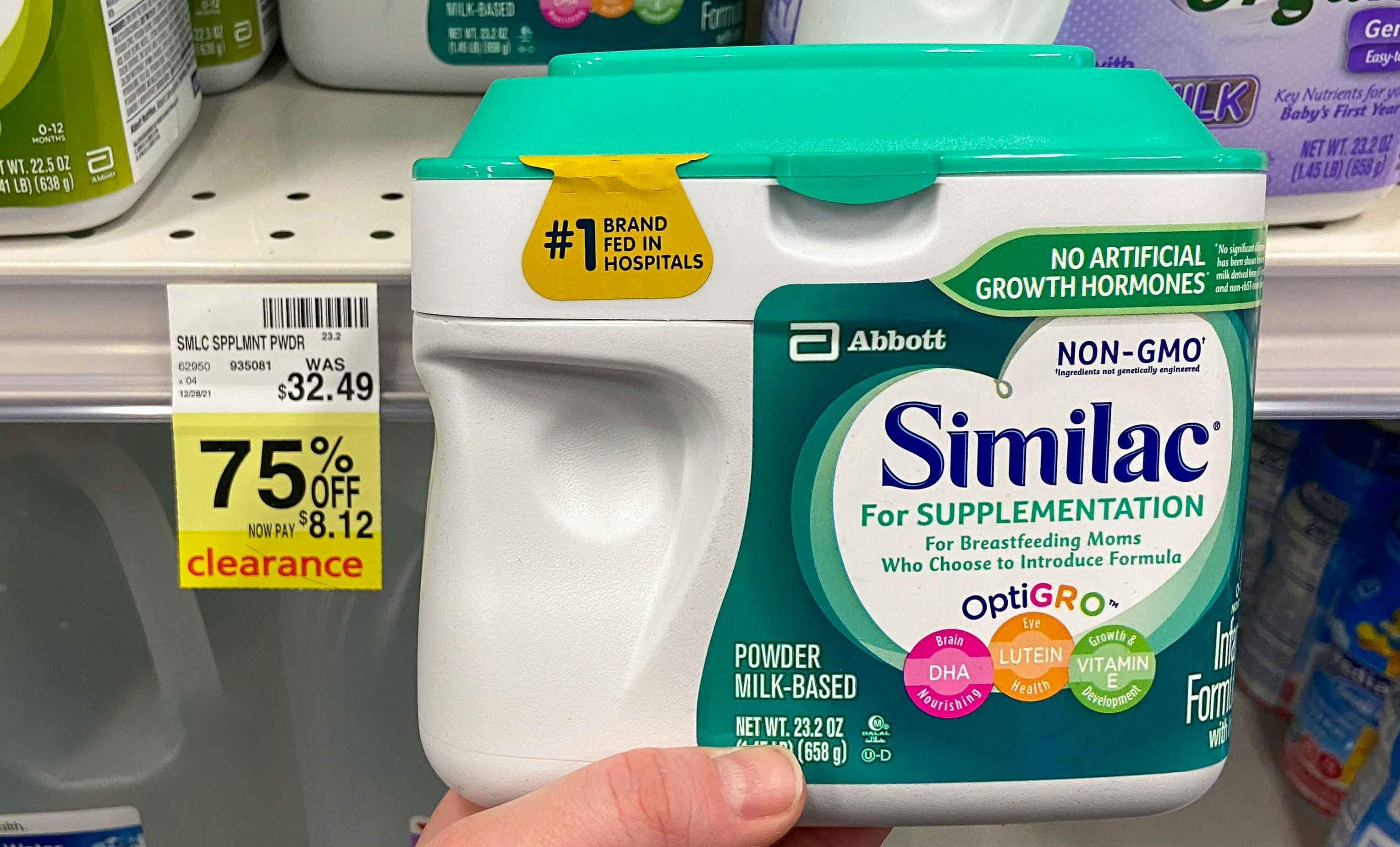 A person's hand holding a container of Similac next to a sale tag for 75% off in CVS.