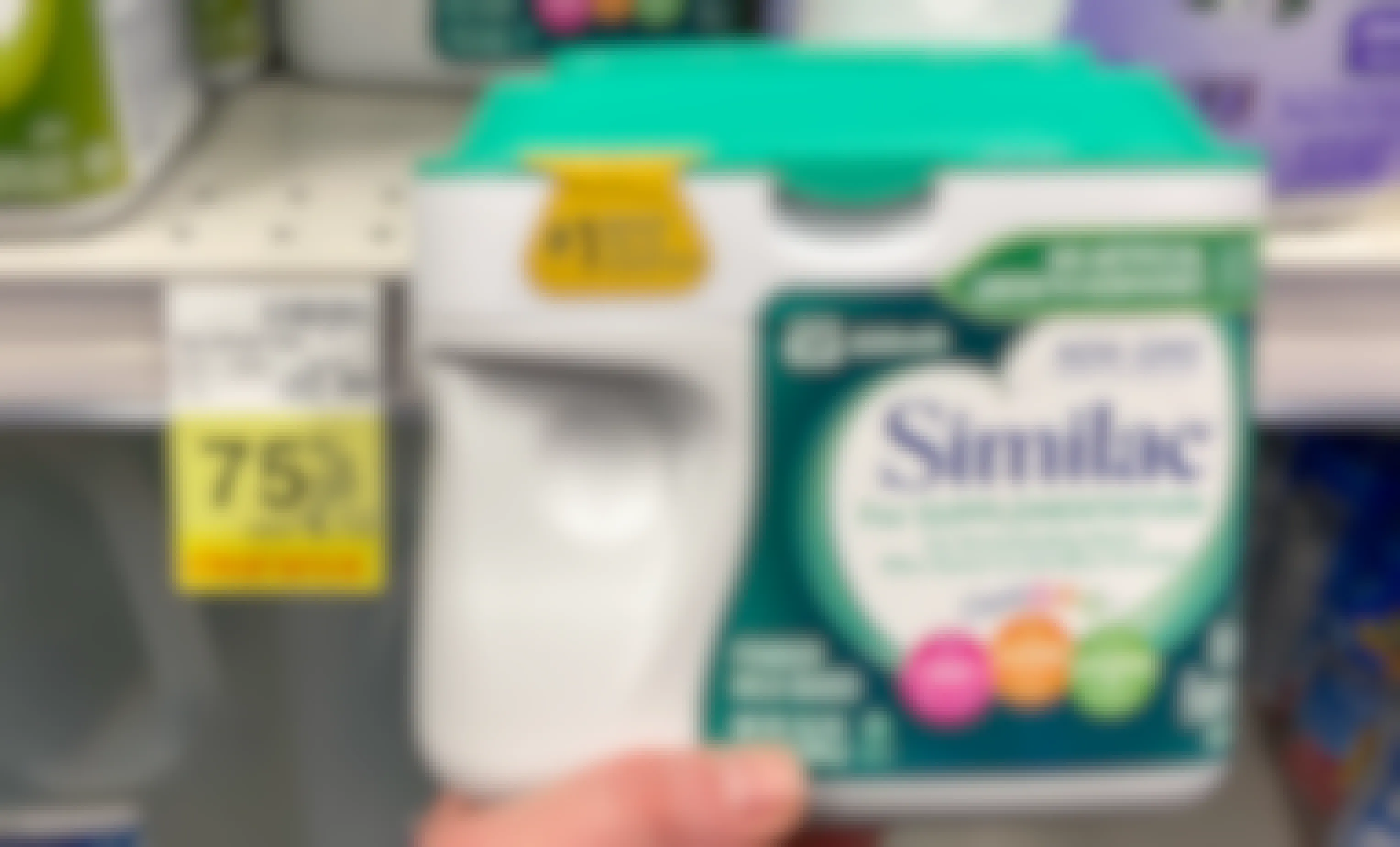 A person's hand holding a container of Similac next to a sale tag for 75% off in CVS.