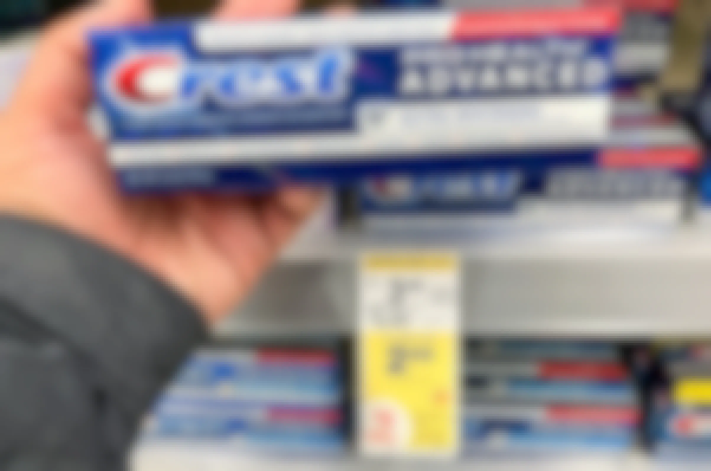 a hand holding a box of crest pro healthy advanced toothpaste at the drug store