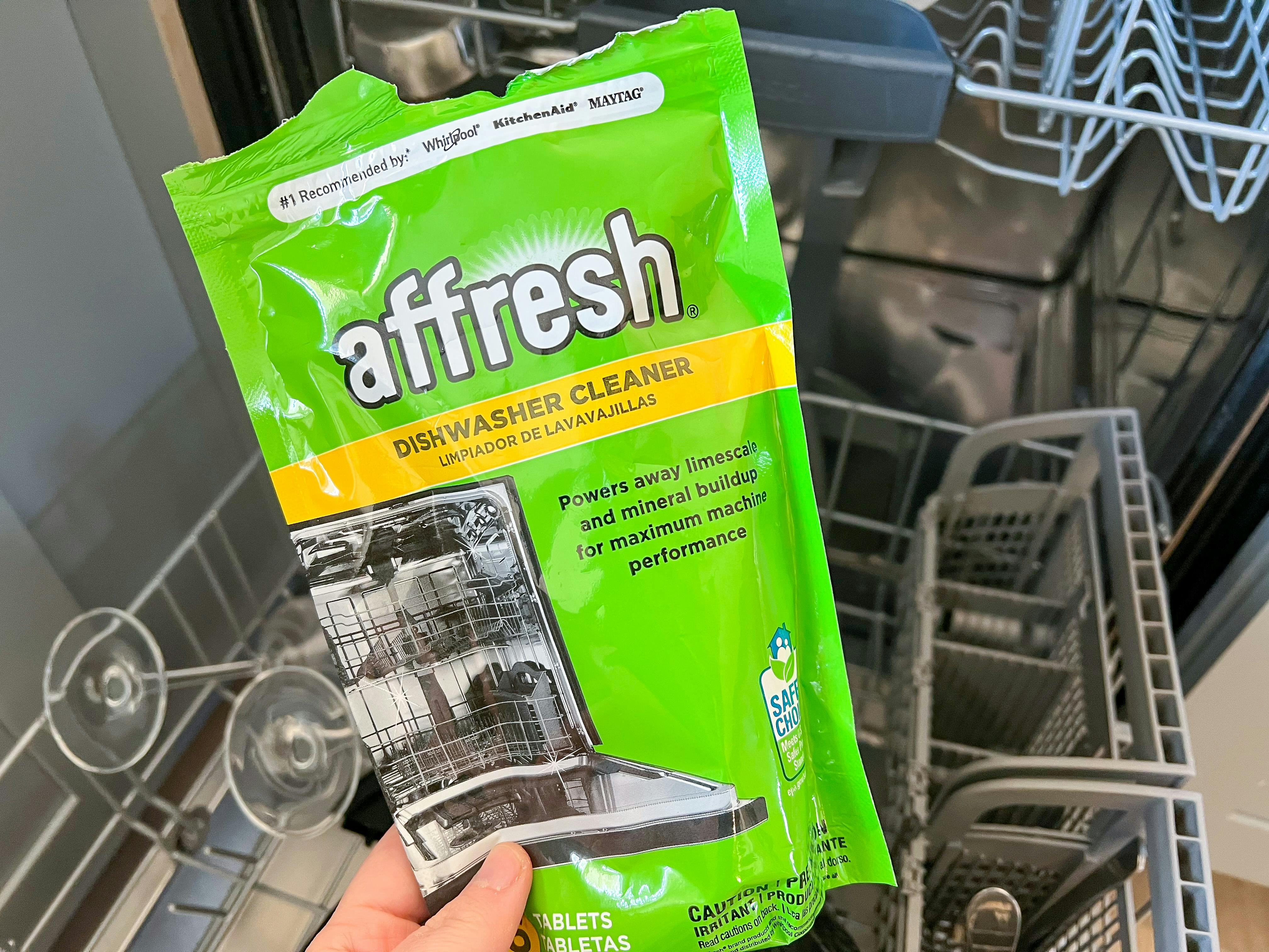 someone holding affresh dishwasher cleaner in front of a dishwasher