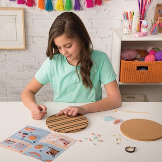 A girl doing crafts at a table with cork board circles