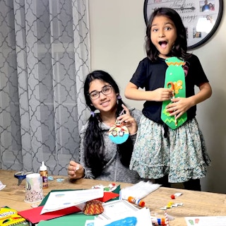 Two young girls sitting at a dining table doing crafts